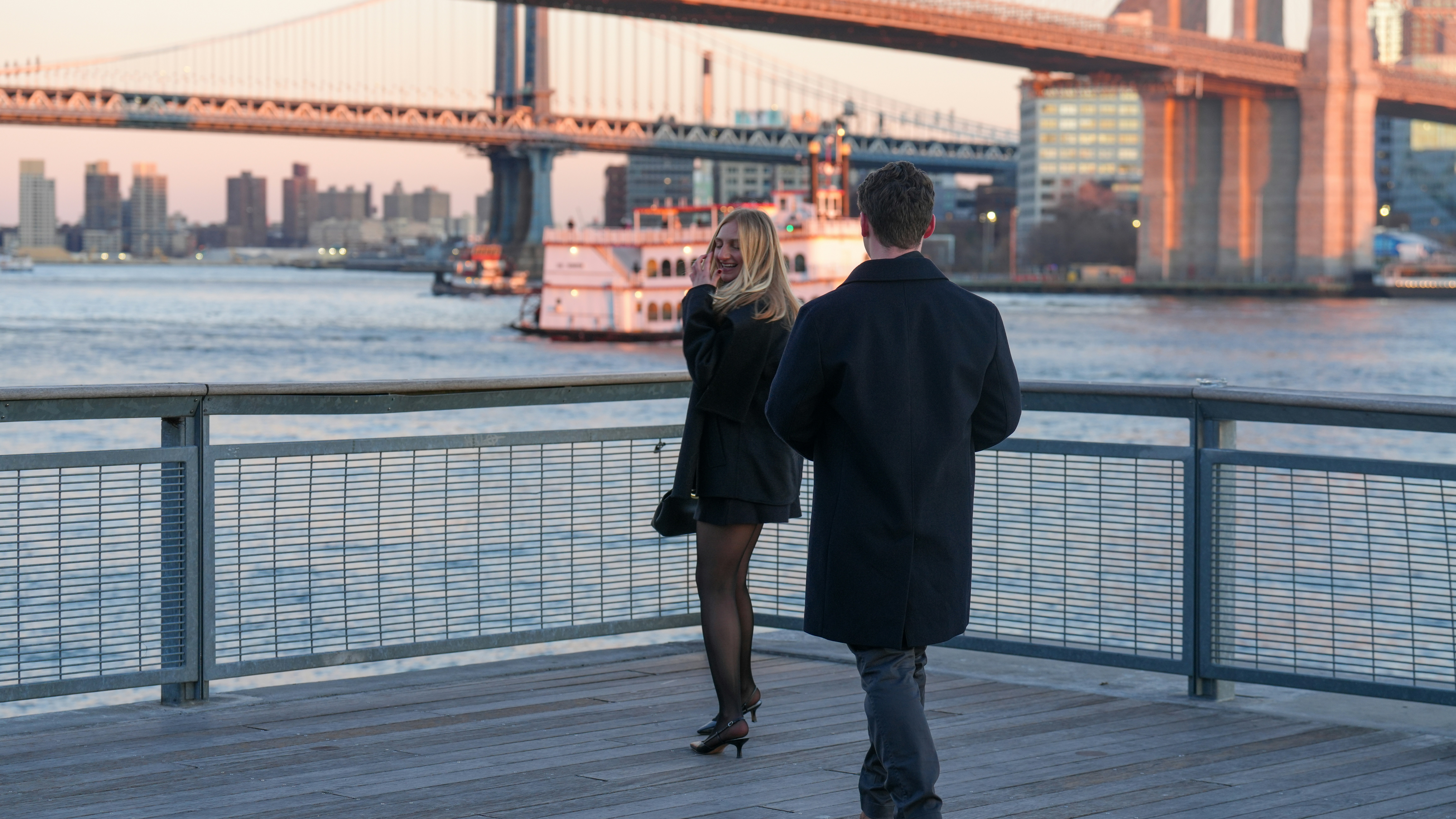 Couple by the water with a bridge in the background