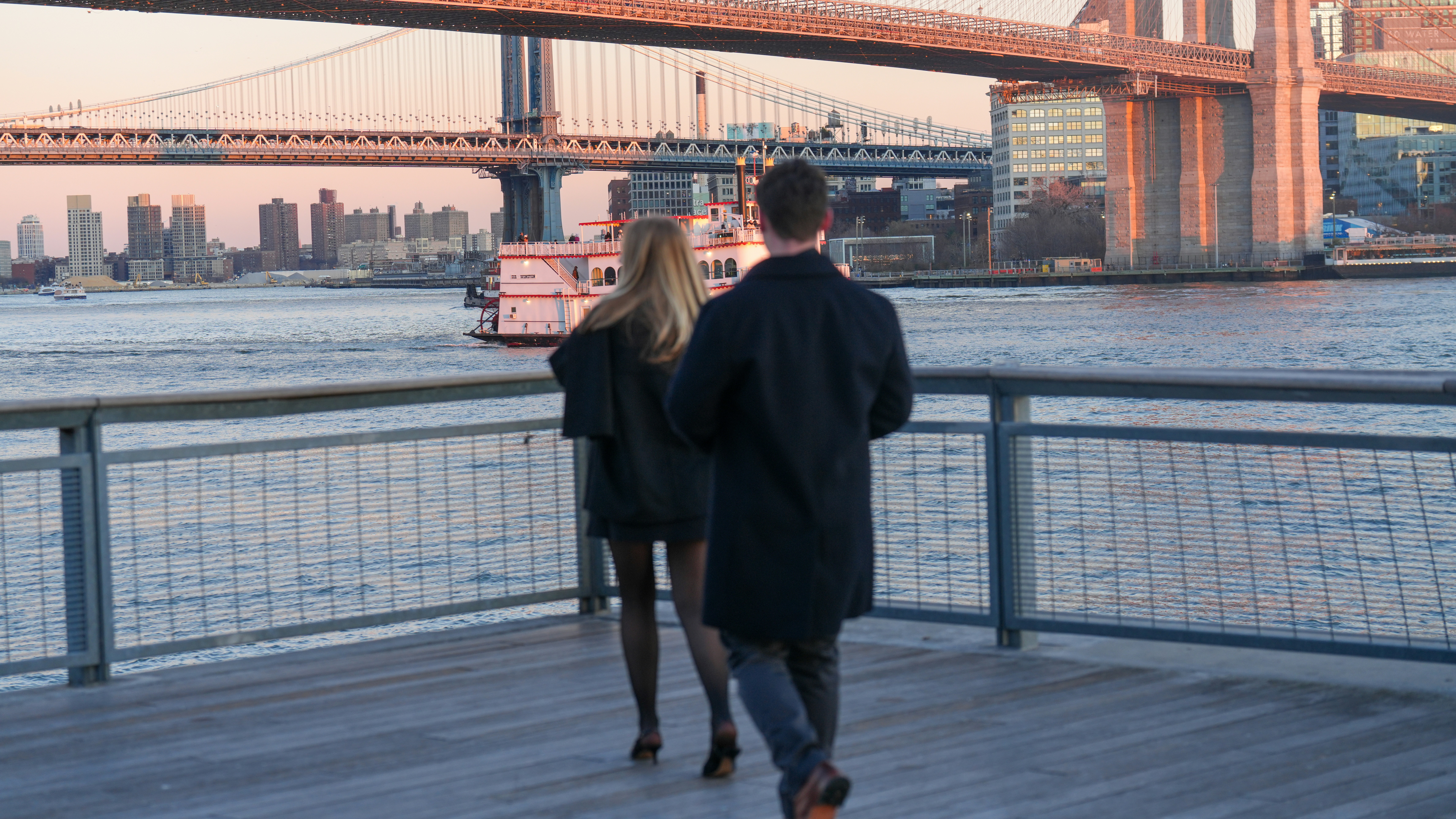 Couple walking towards a bridge at sunset