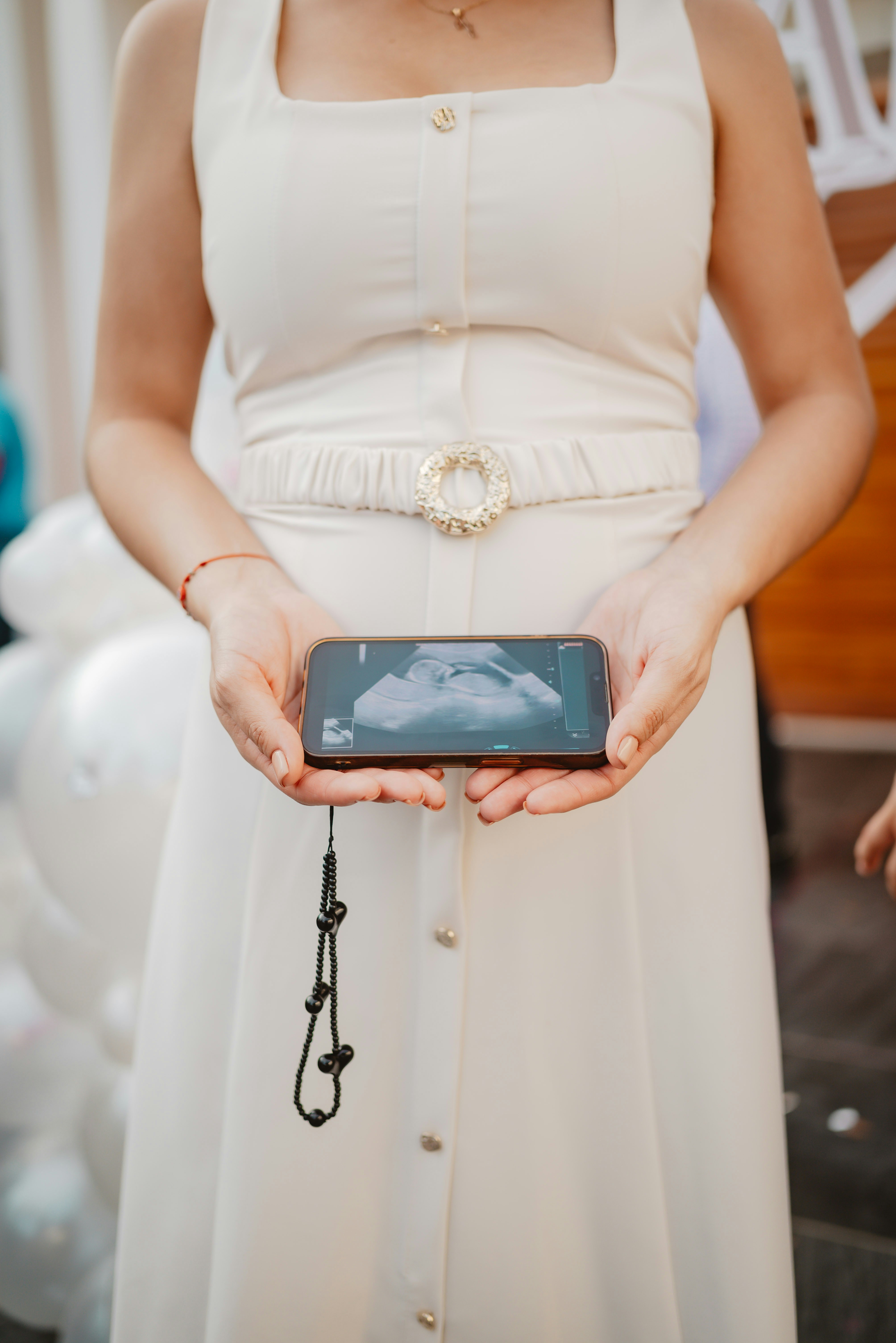 Frau hält Handy und zeigt Ultraschallbild an