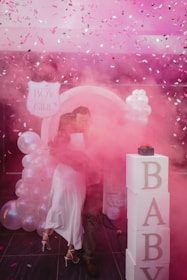 Couple embraced in pink smoke with "baby" blocks.
