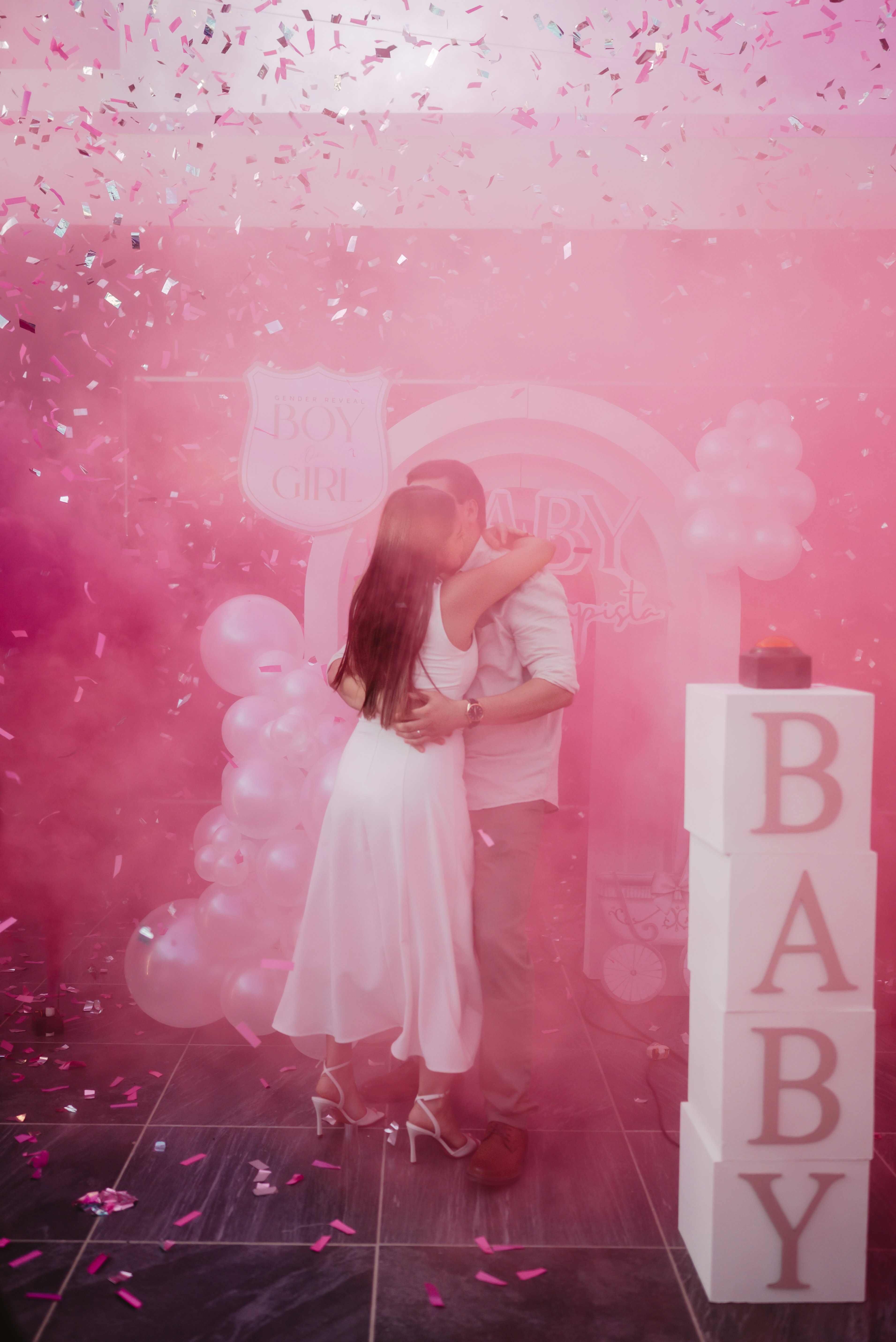 Couple hugging amidst pink smoke and confetti.