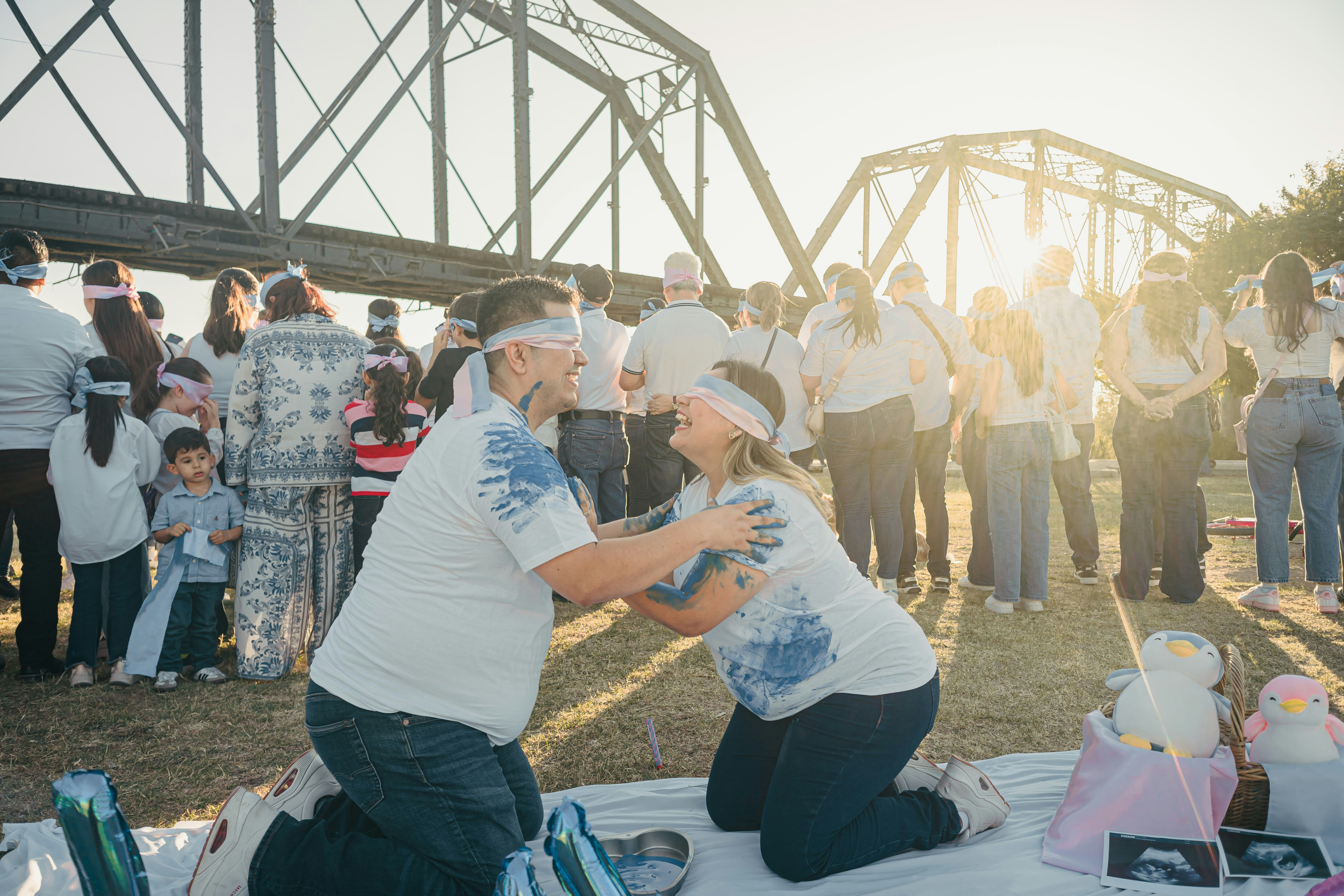 Couple kneeling outdoors during a gender reveal party.
