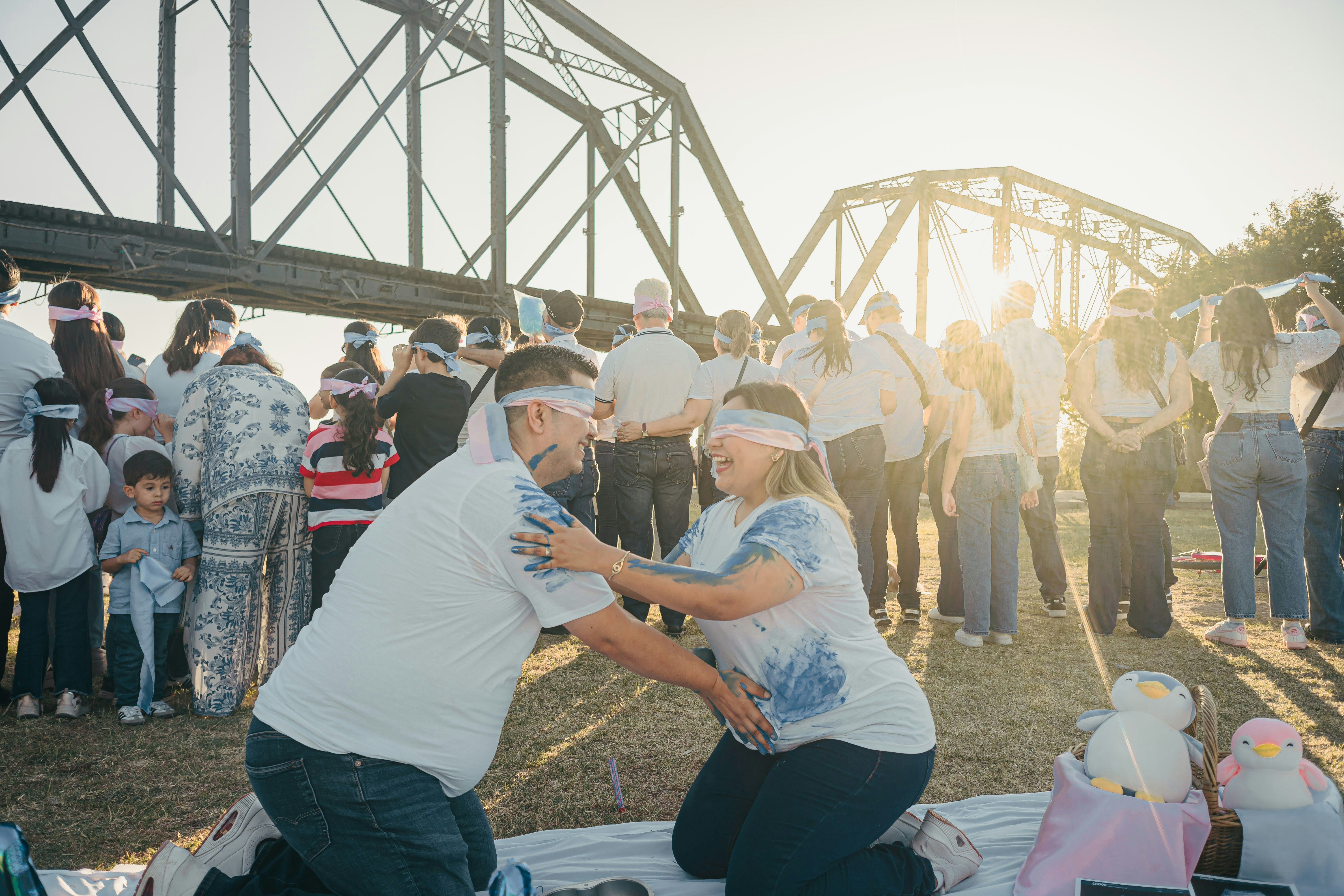 Couple blindfolded playing game near bridge at sunset