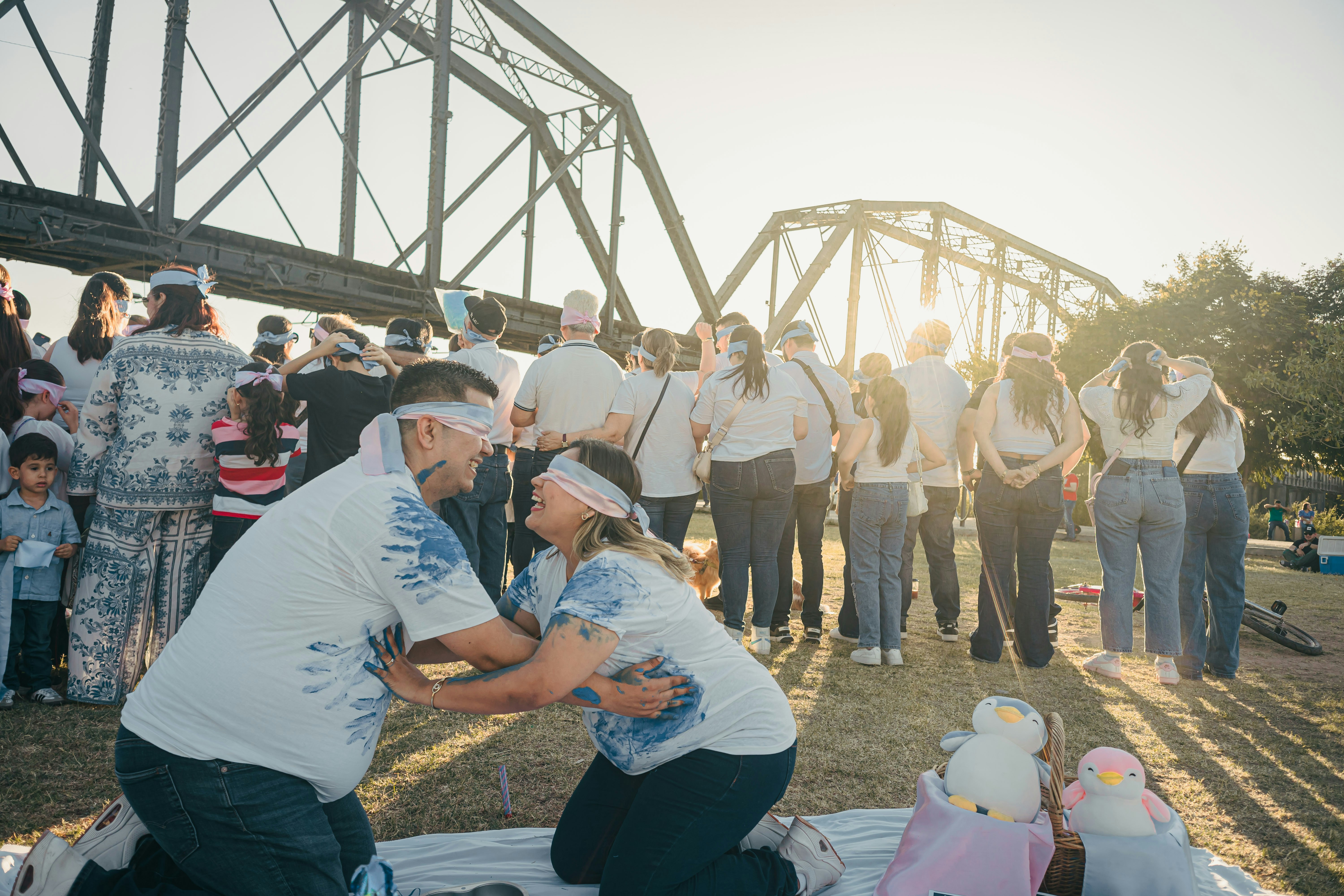 Couple blindfolded, kneeling outdoors with crowd watching