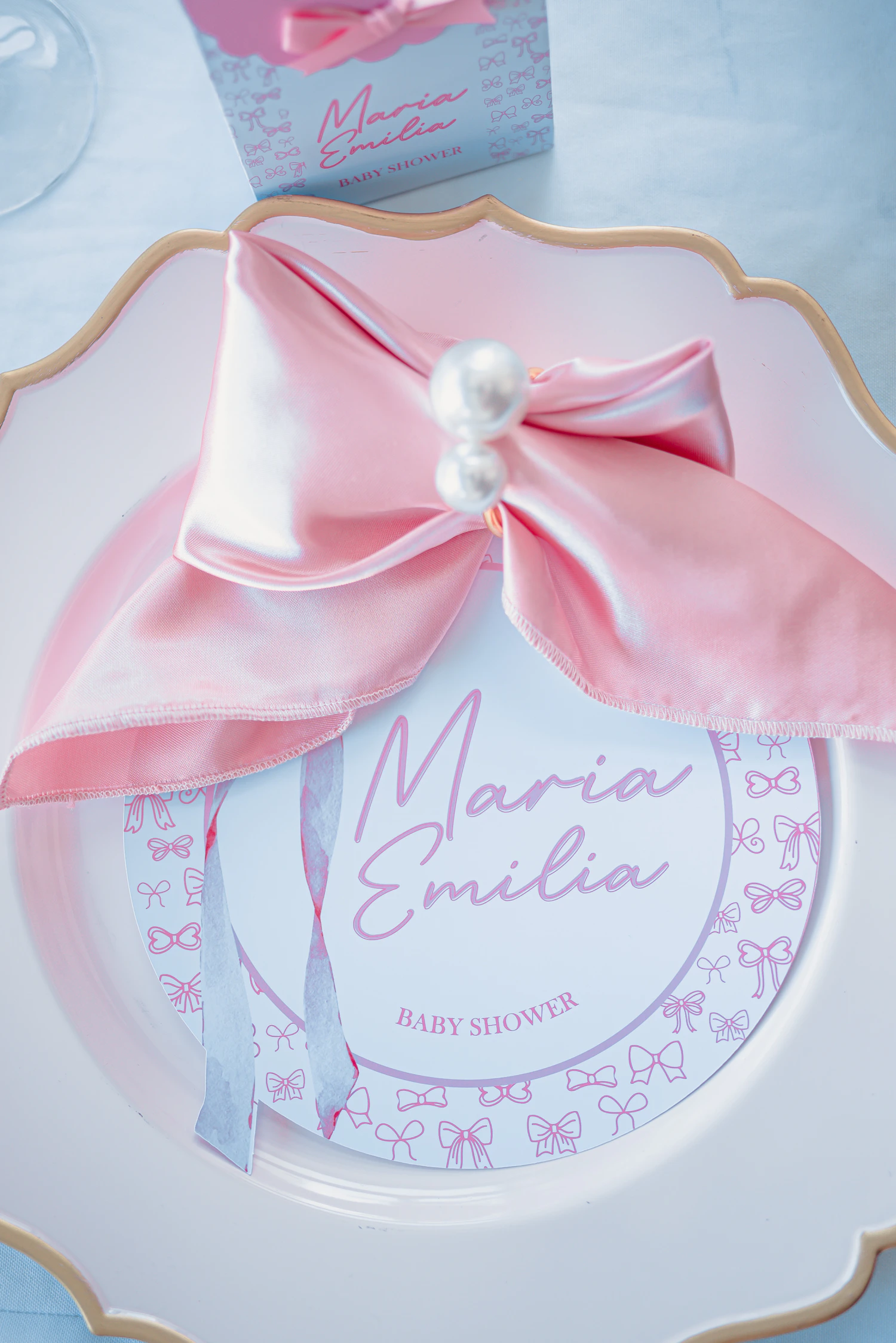 Pink baby shower place setting with decorative plate, ribbon and celebration name card