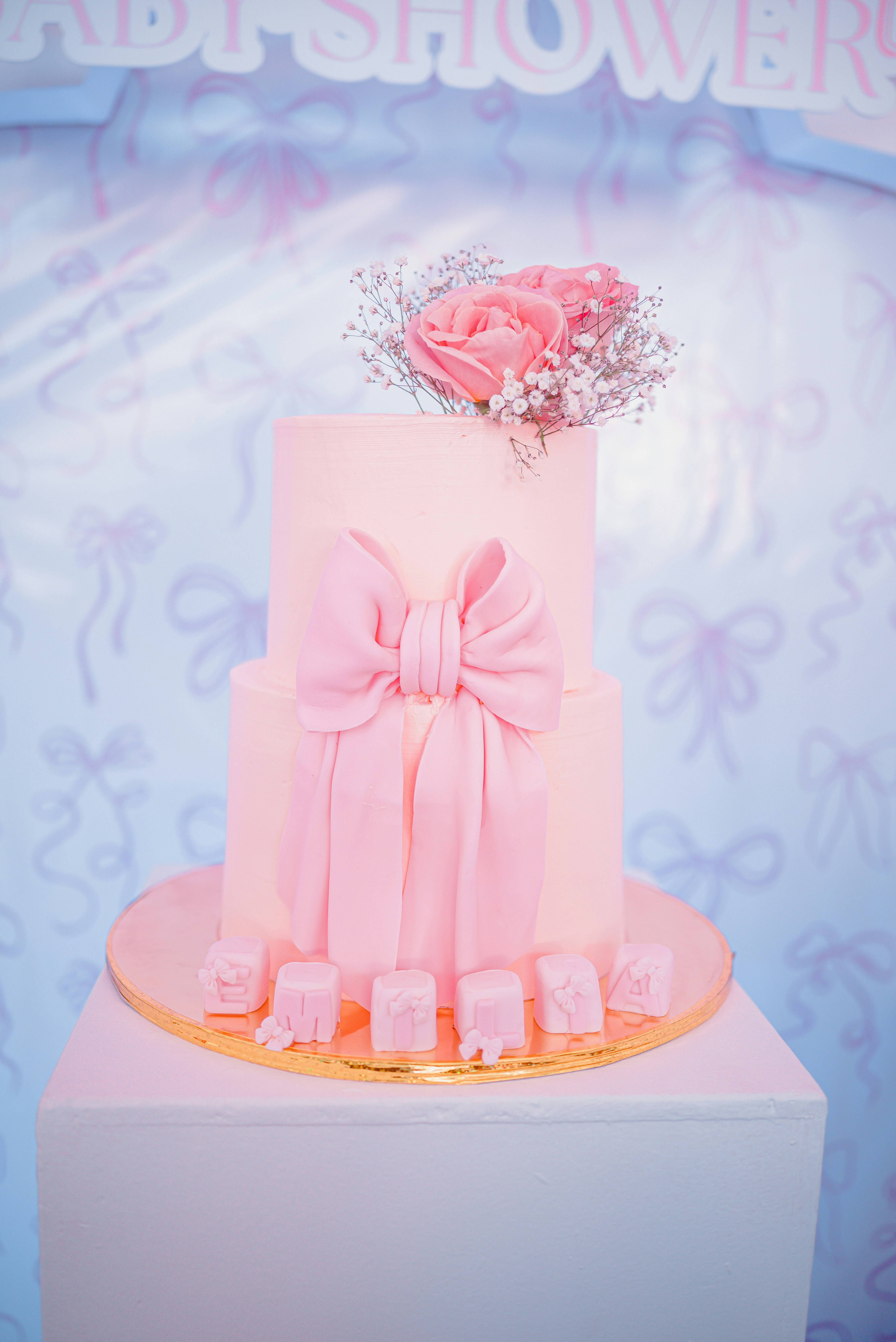 A pink two-tiered cake with a large bow decoration.