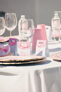 A table setting with pink party favors and glasses.
