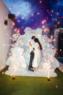 Couple hugging amidst blue smoke and confetti at gender reveal