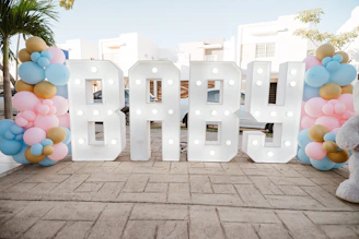 Large illuminated letters spell out baby with balloons.