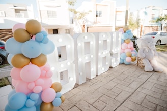 Illuminated 'baby' sign with balloons and teddy bear