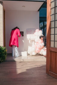 Two women decorating with pink and white balloons.