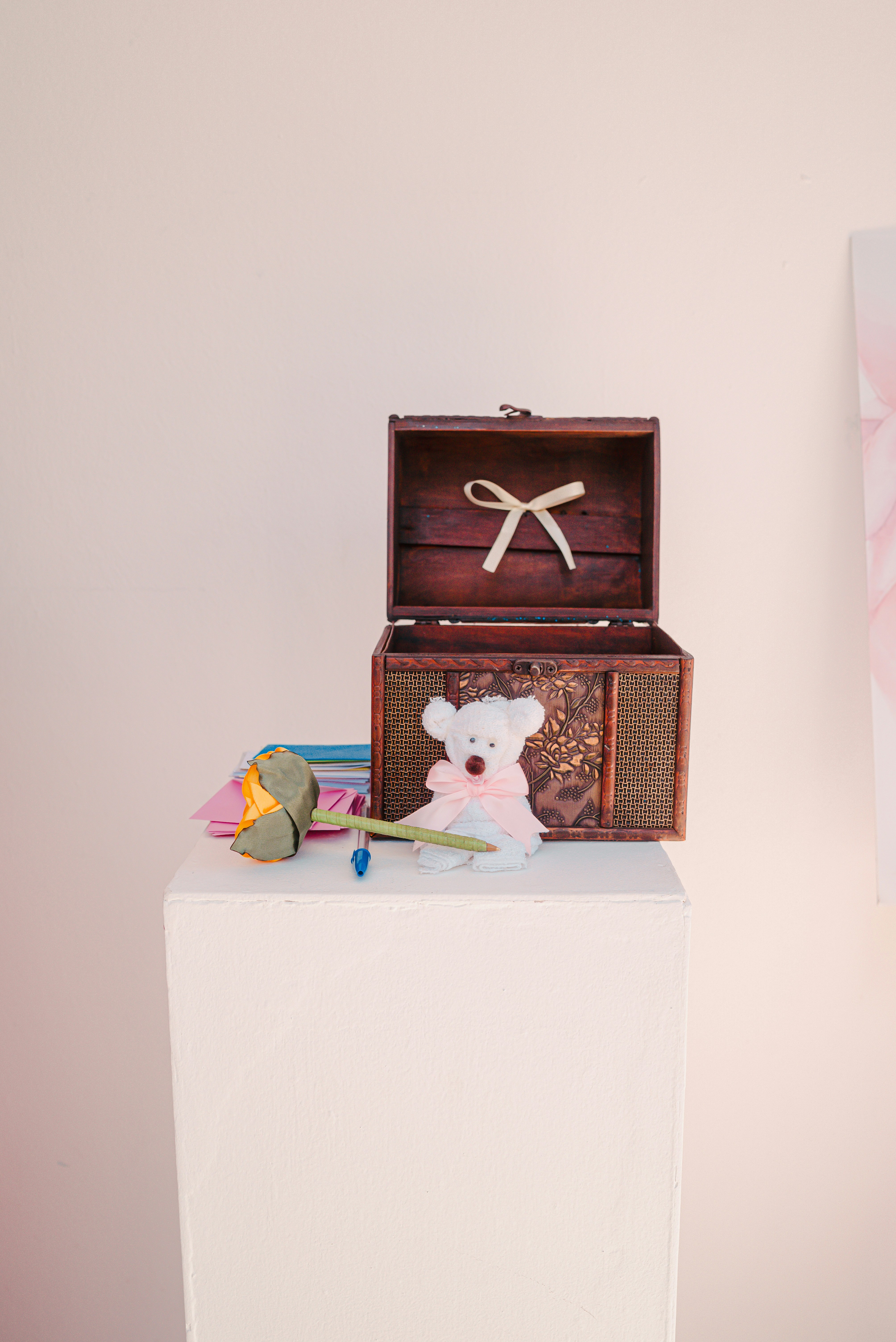 Teddy bear and rose next to an open wooden chest.