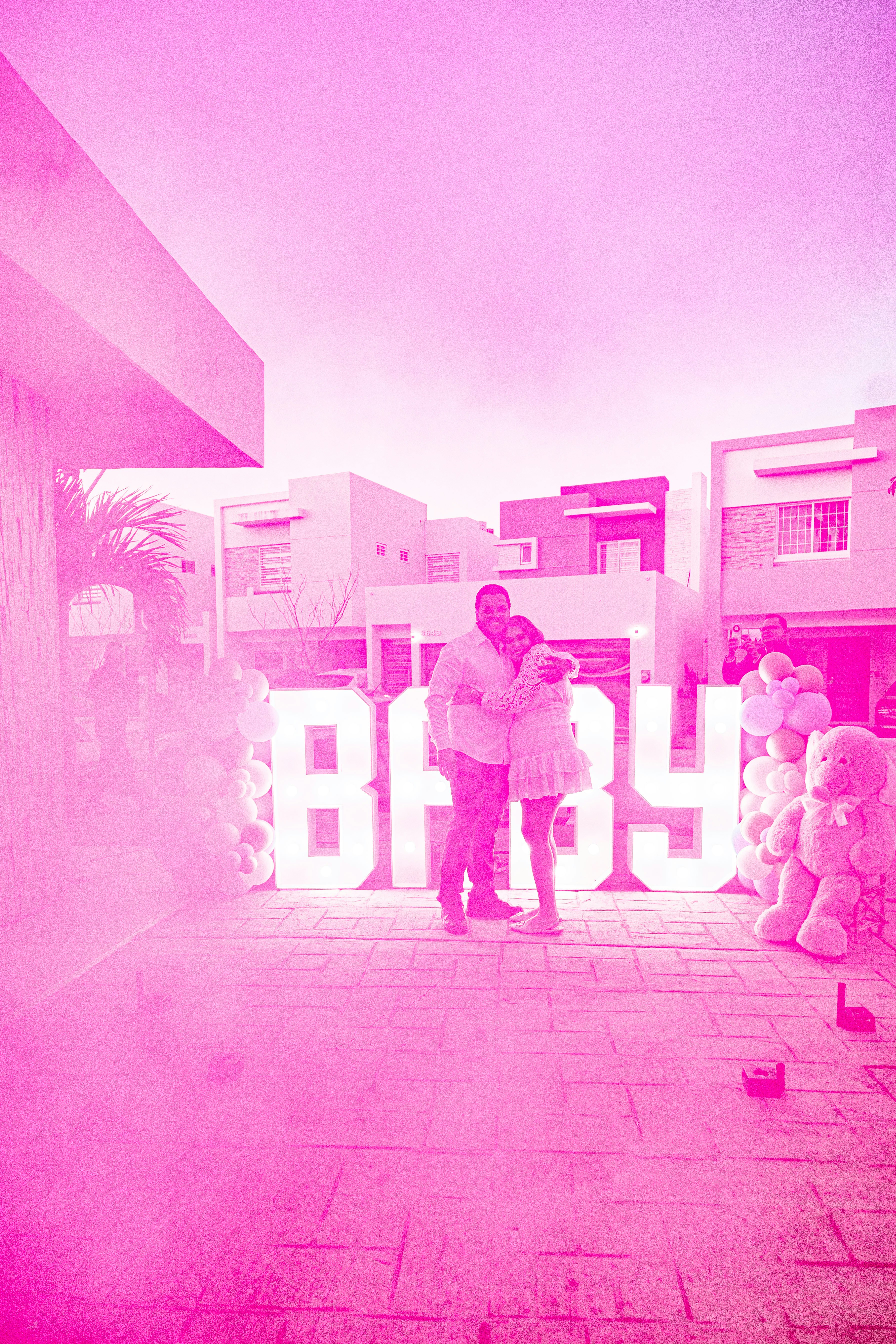 Couple hugging in front of large "baby" letters