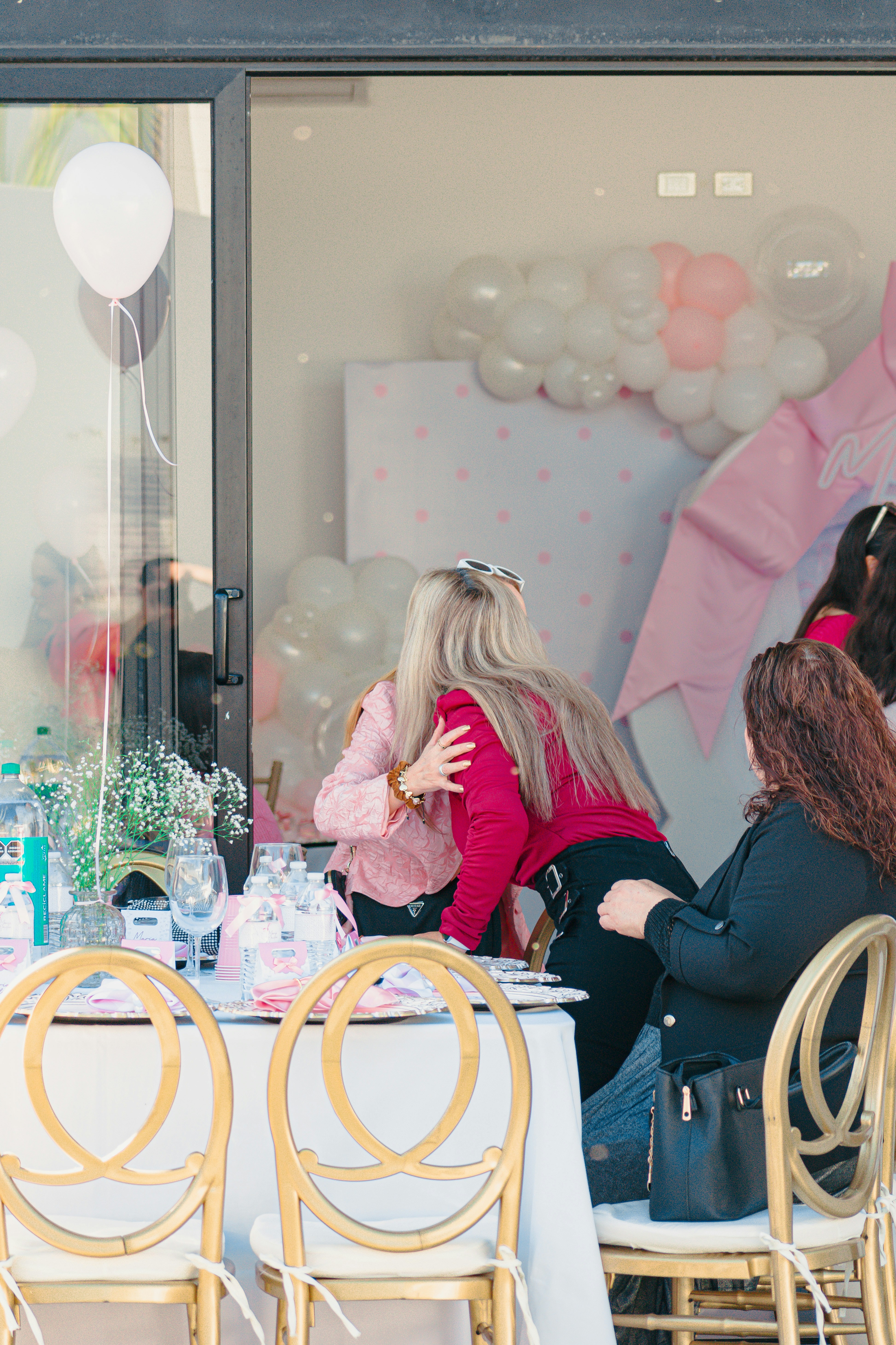 Zwei Frauen umarmen sich auf einer Party mit Luftballons und Dekorationen.