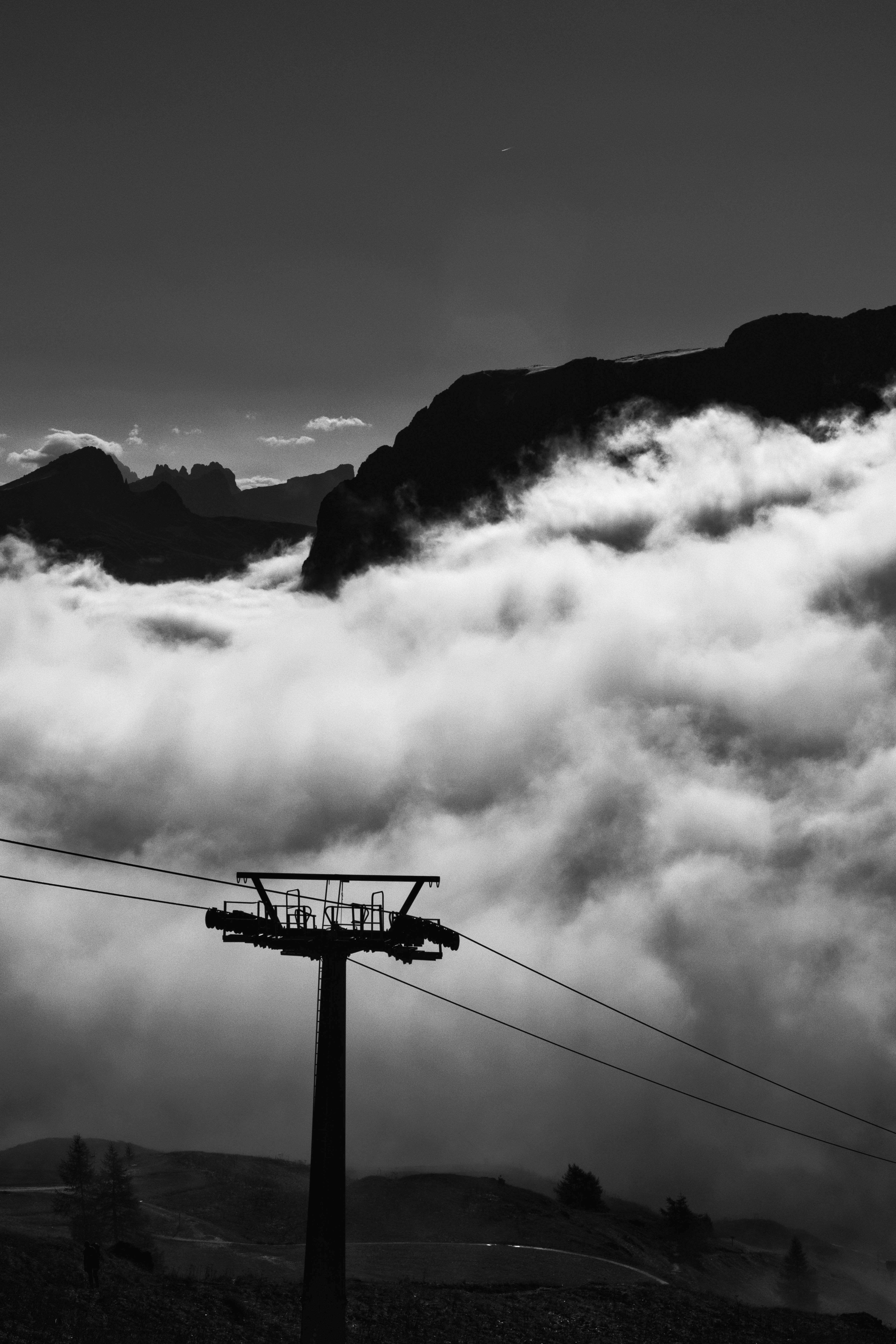 Ski lift tower above clouds in mountains