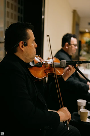 Musicians playing violins in a formal setting.
