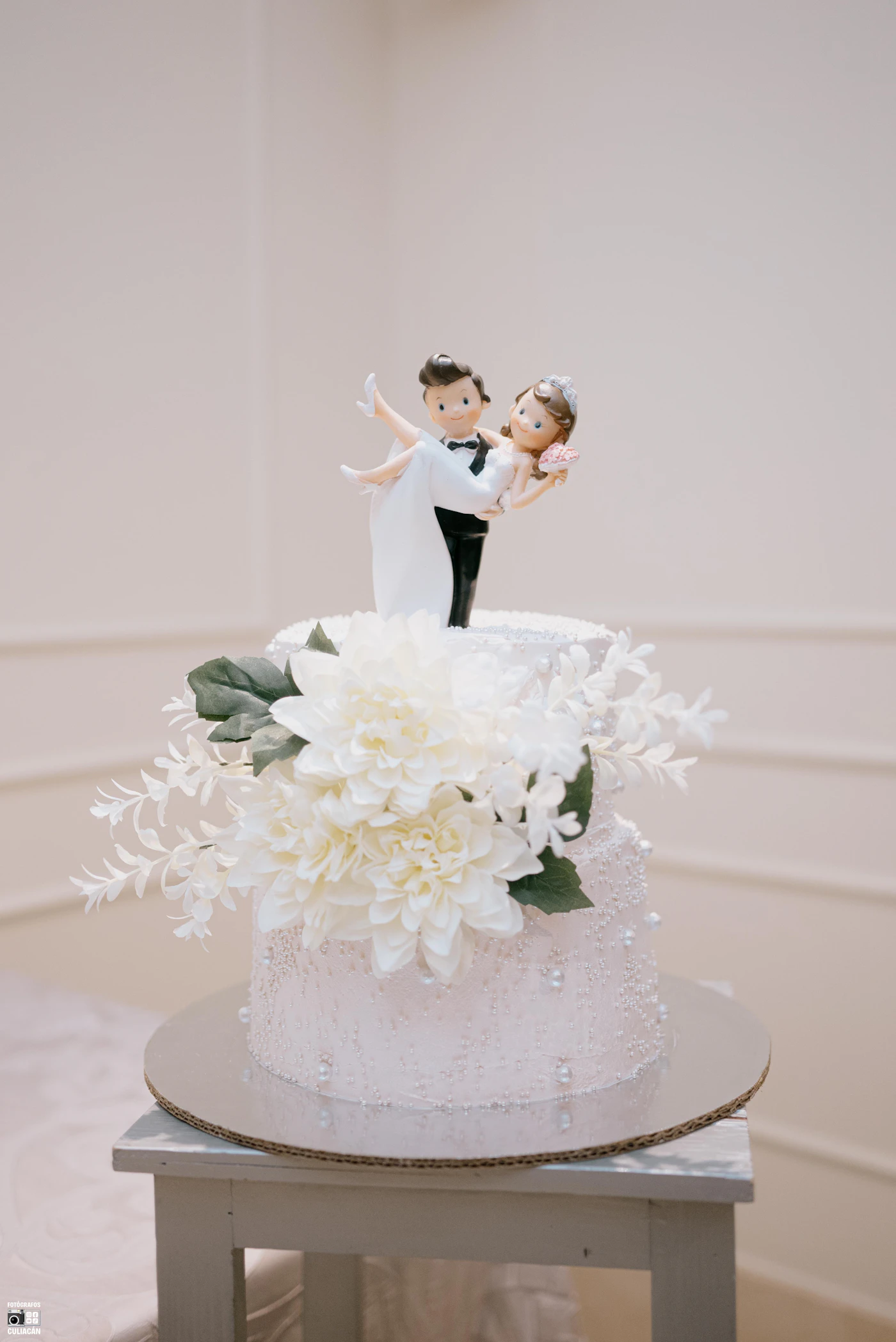 How to make your own wedding cake topper — A handmade paper wedding cake topper displayed on a tiered white cake.