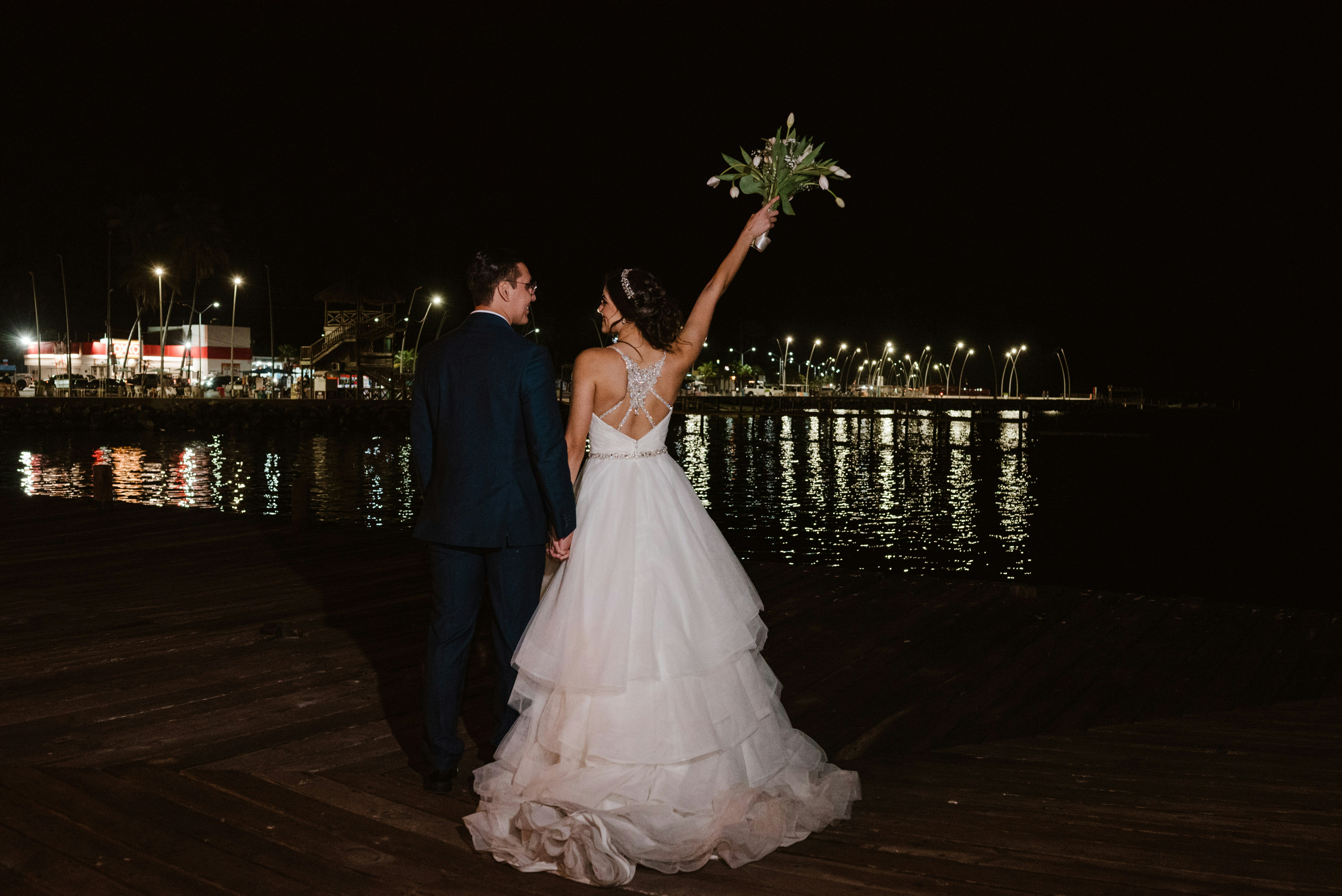 Bride and groom celebrating by the water at night