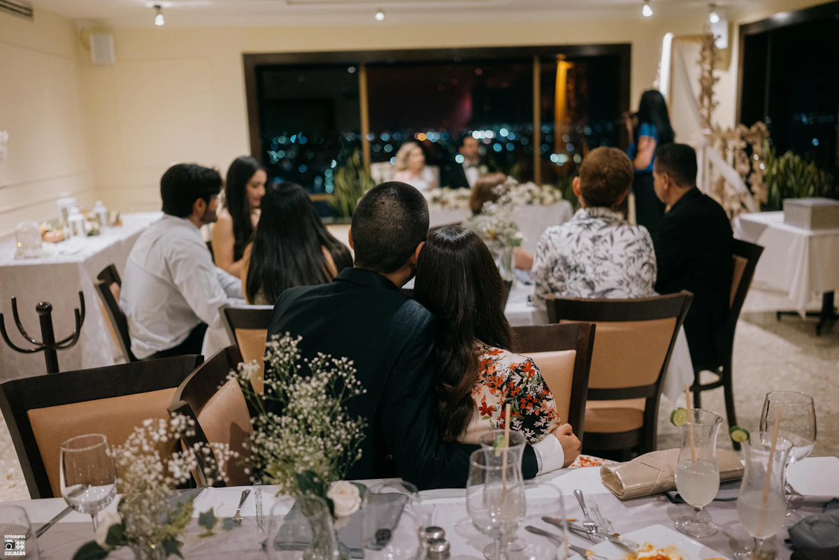 Guests holding drinks at an evening reception lit by hanging bulbs