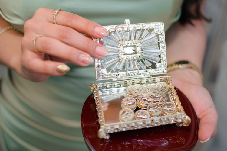 Woman holding an ornate jewelry box filled with gold coins, representing the careful curation of a precious metals portfolio