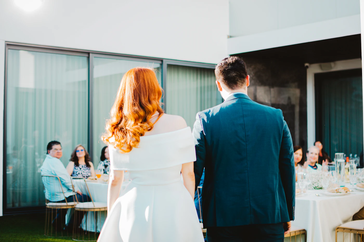 Bride and groom walk hand in hand toward their seated guests