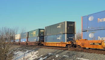 Freight train carrying shipping containers on tracks.