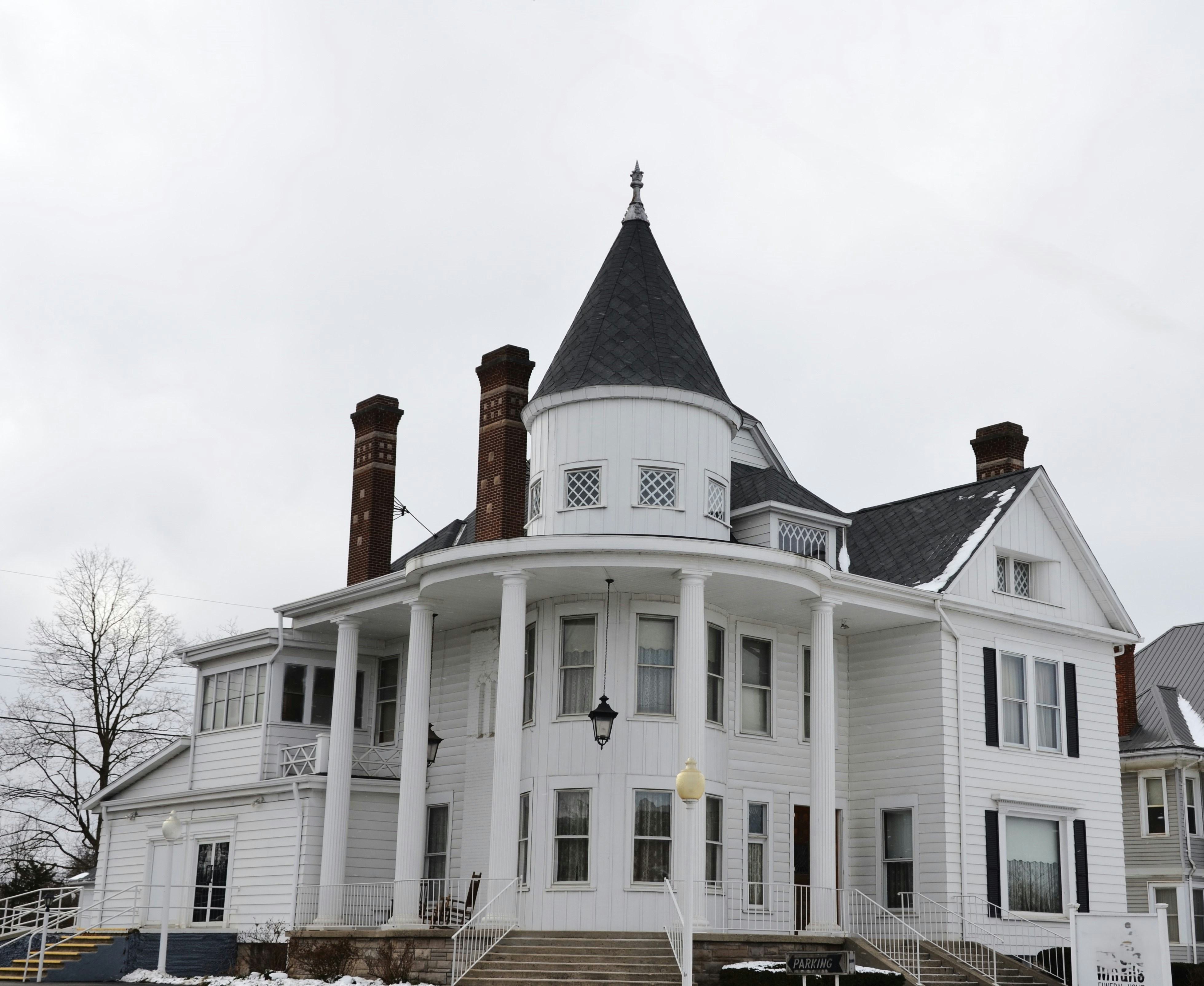 A white victorian house with a conical tower.