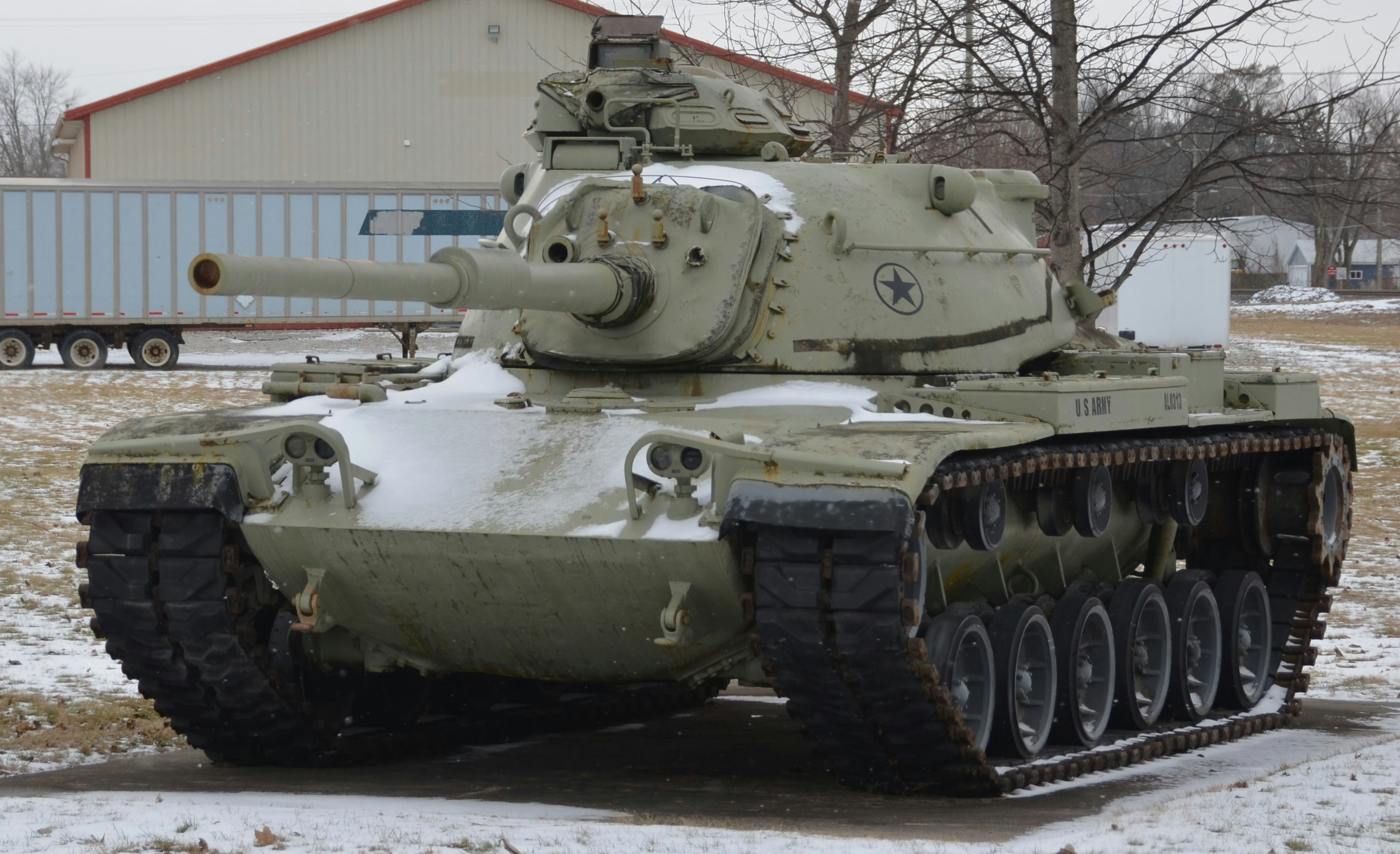 A tan military tank sits in a snowy outdoor setting.