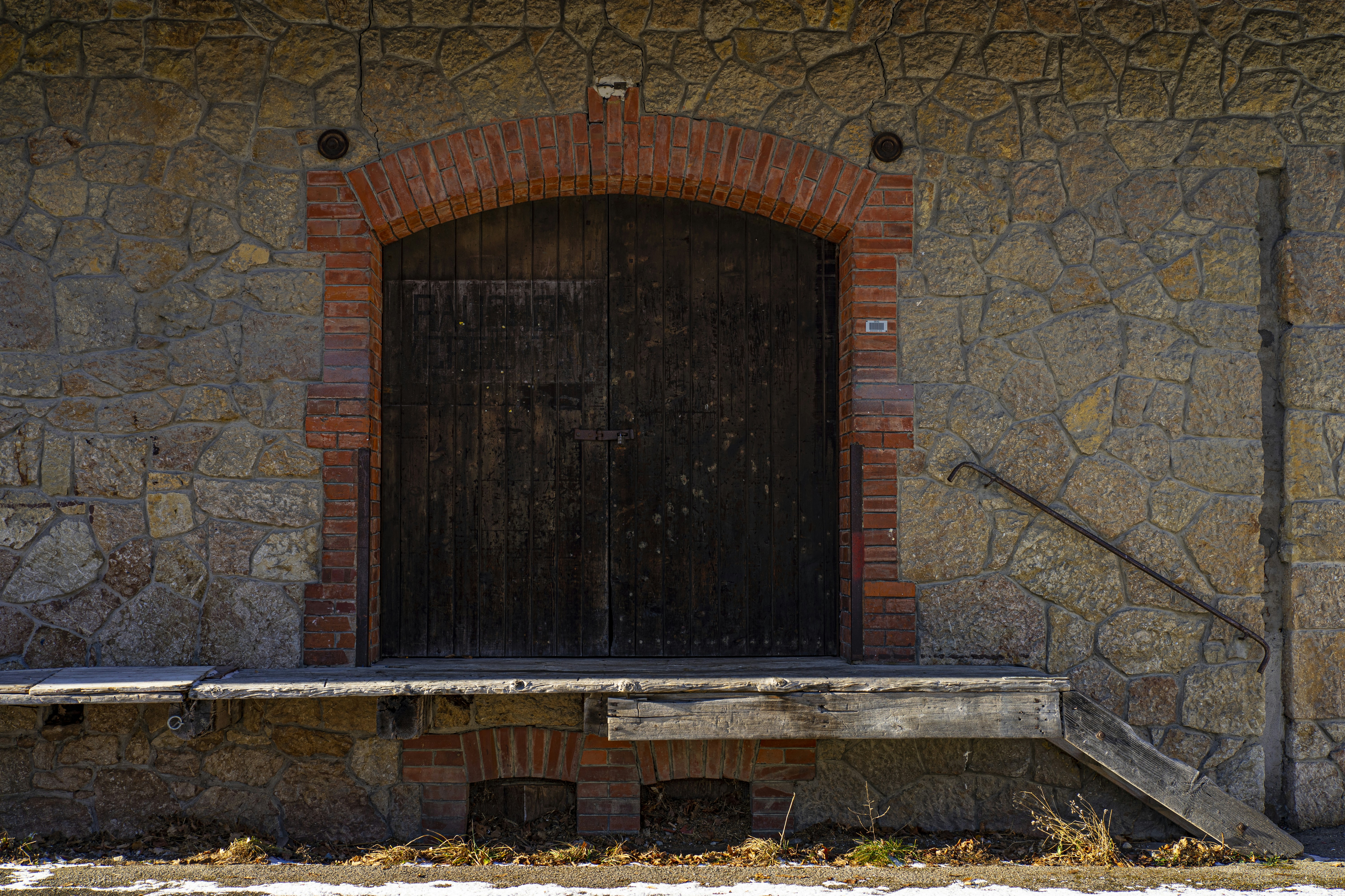 Old wooden door set in stone wall with brick arch
