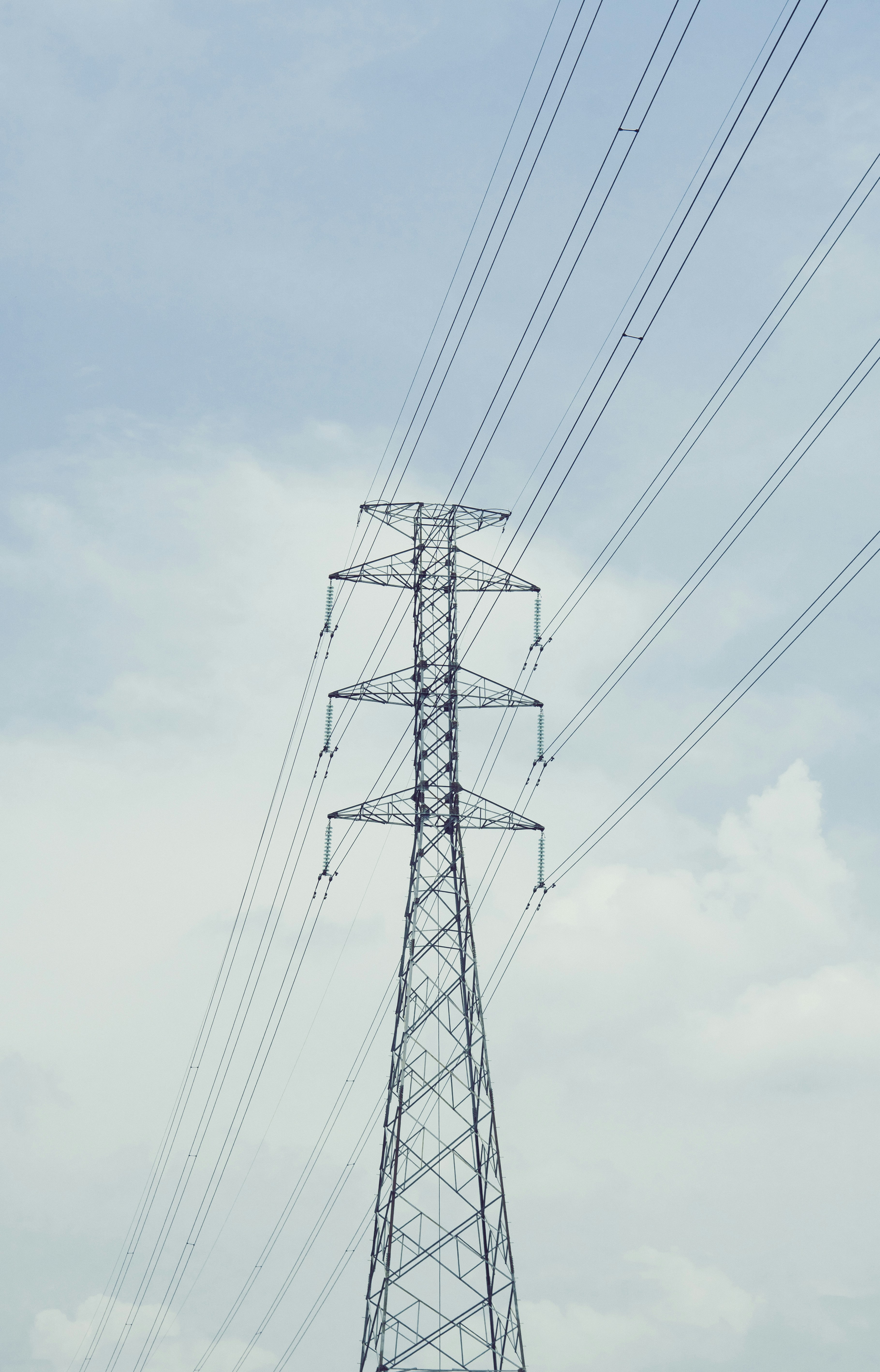 Hoher Stromleitungsturm vor einem wolkigen Himmel