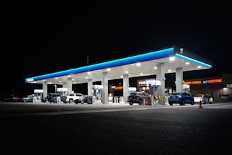 Gas station at night with cars at pumps.
