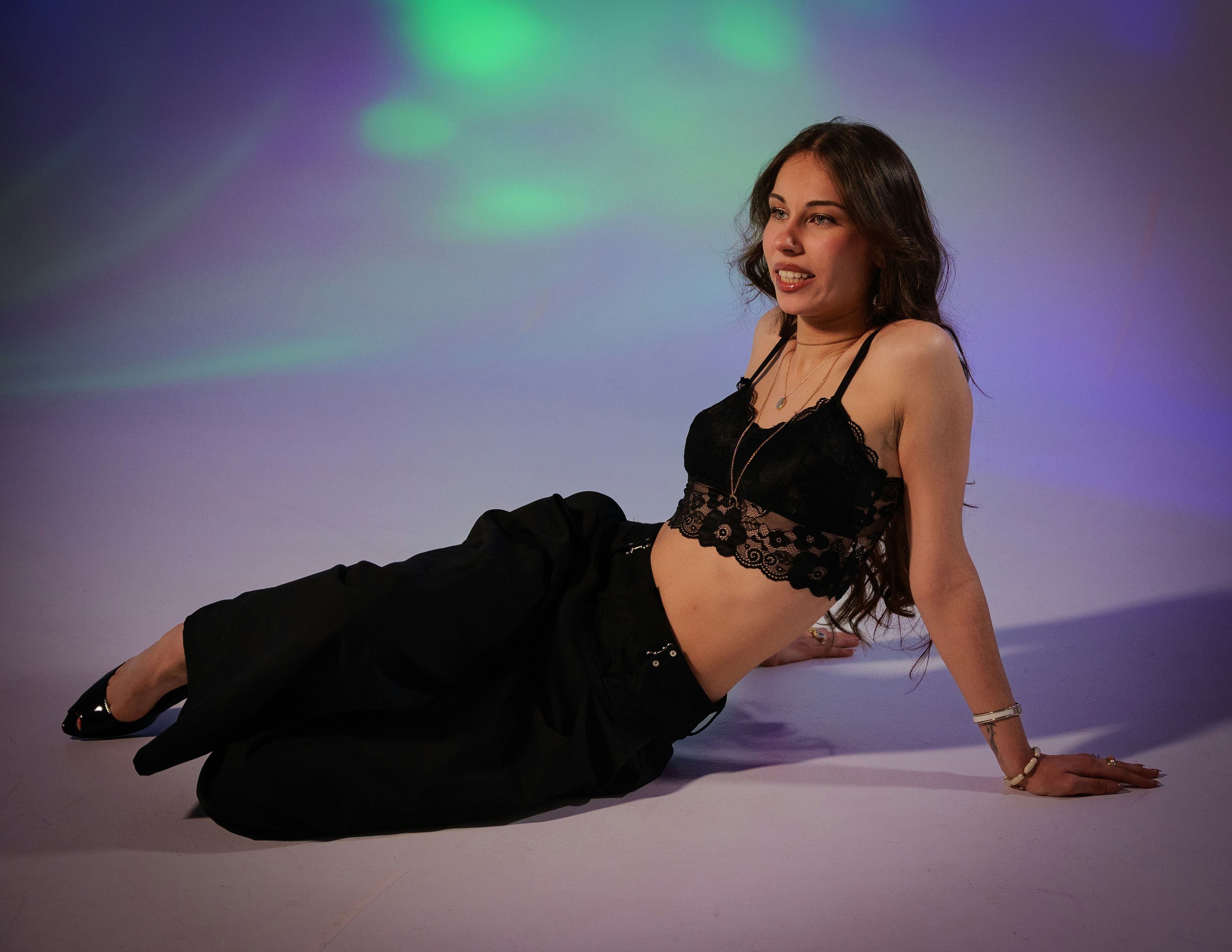 A woman in black lace top and pants poses.