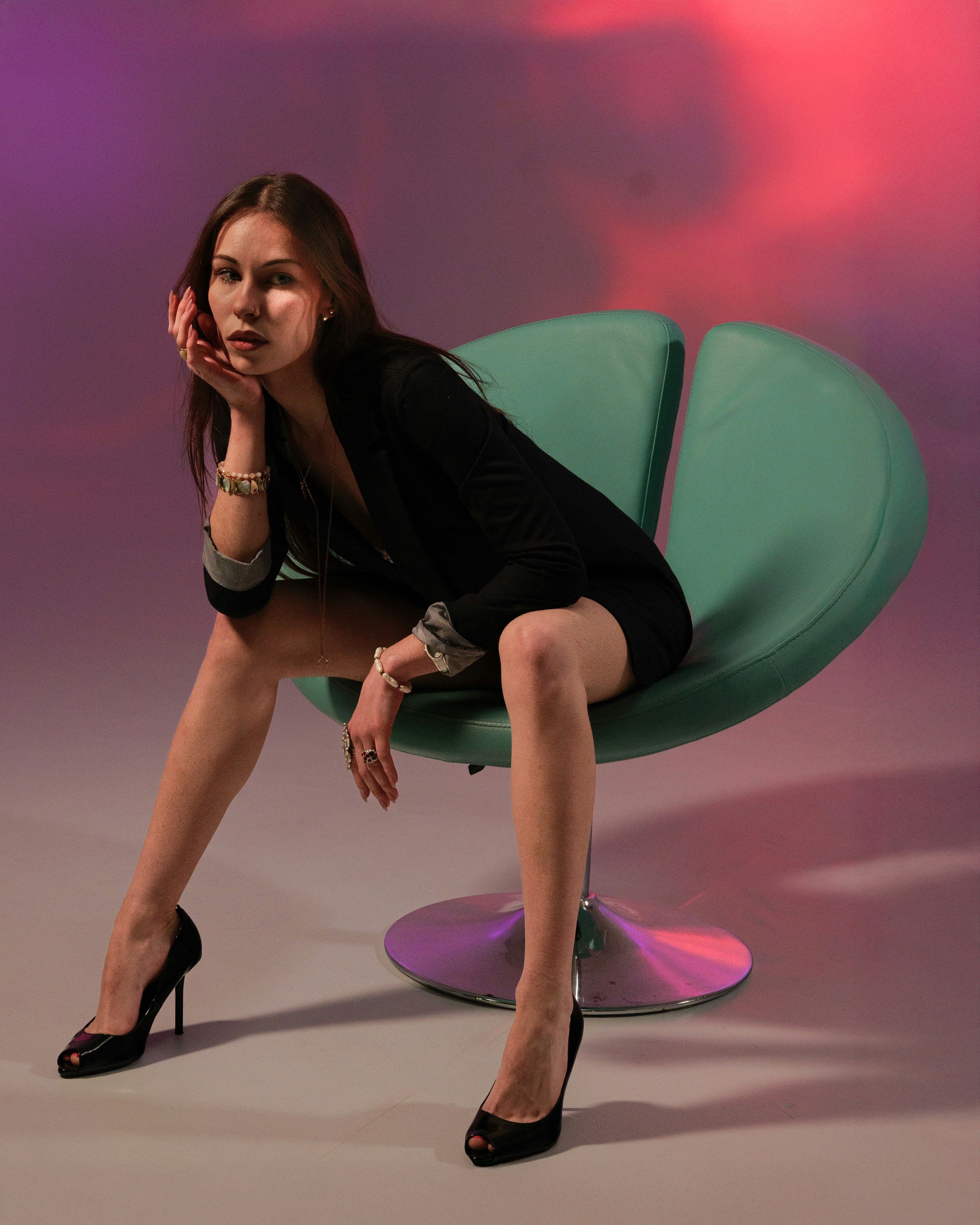 Woman in black dress sitting on a modern chair.