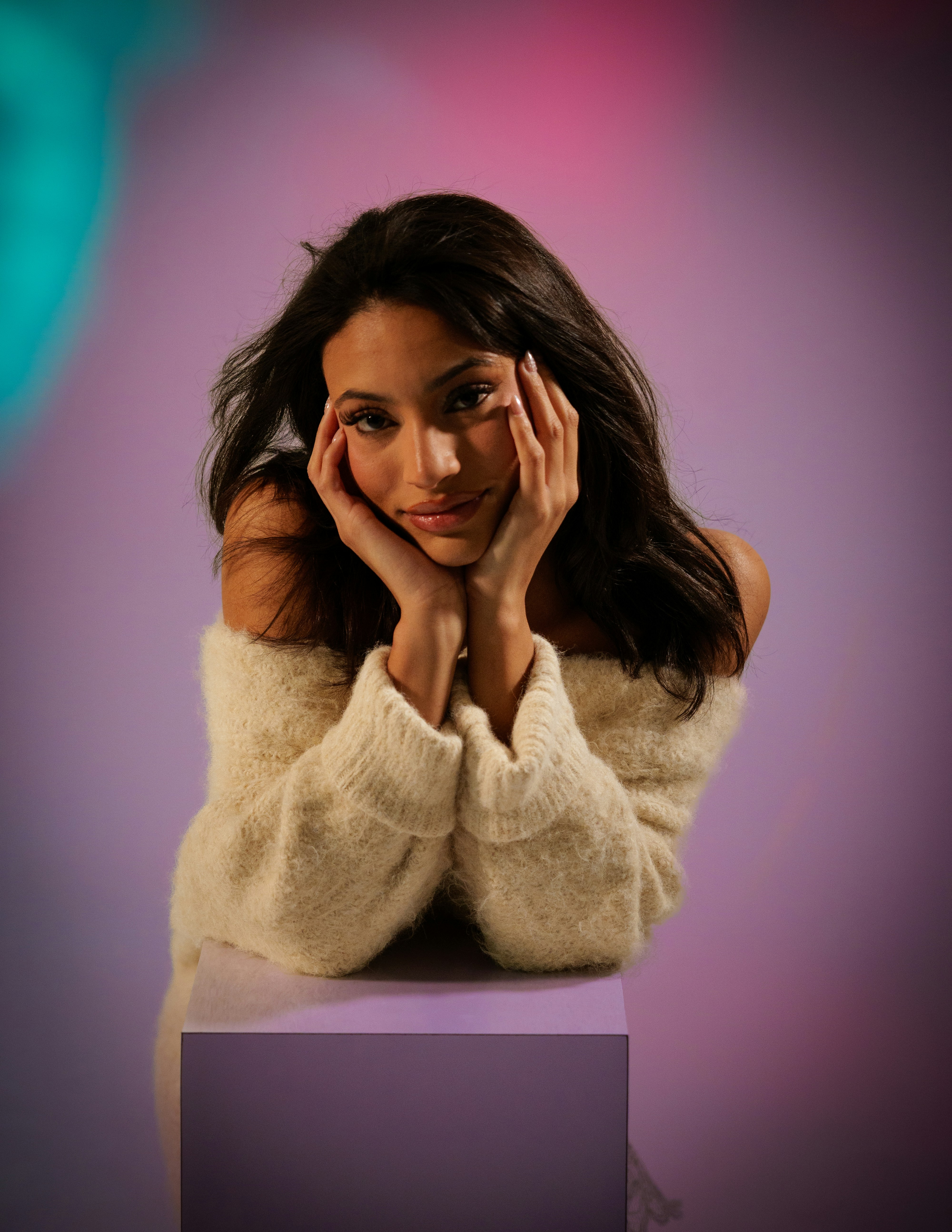 Young woman with hands on cheeks against purple background.