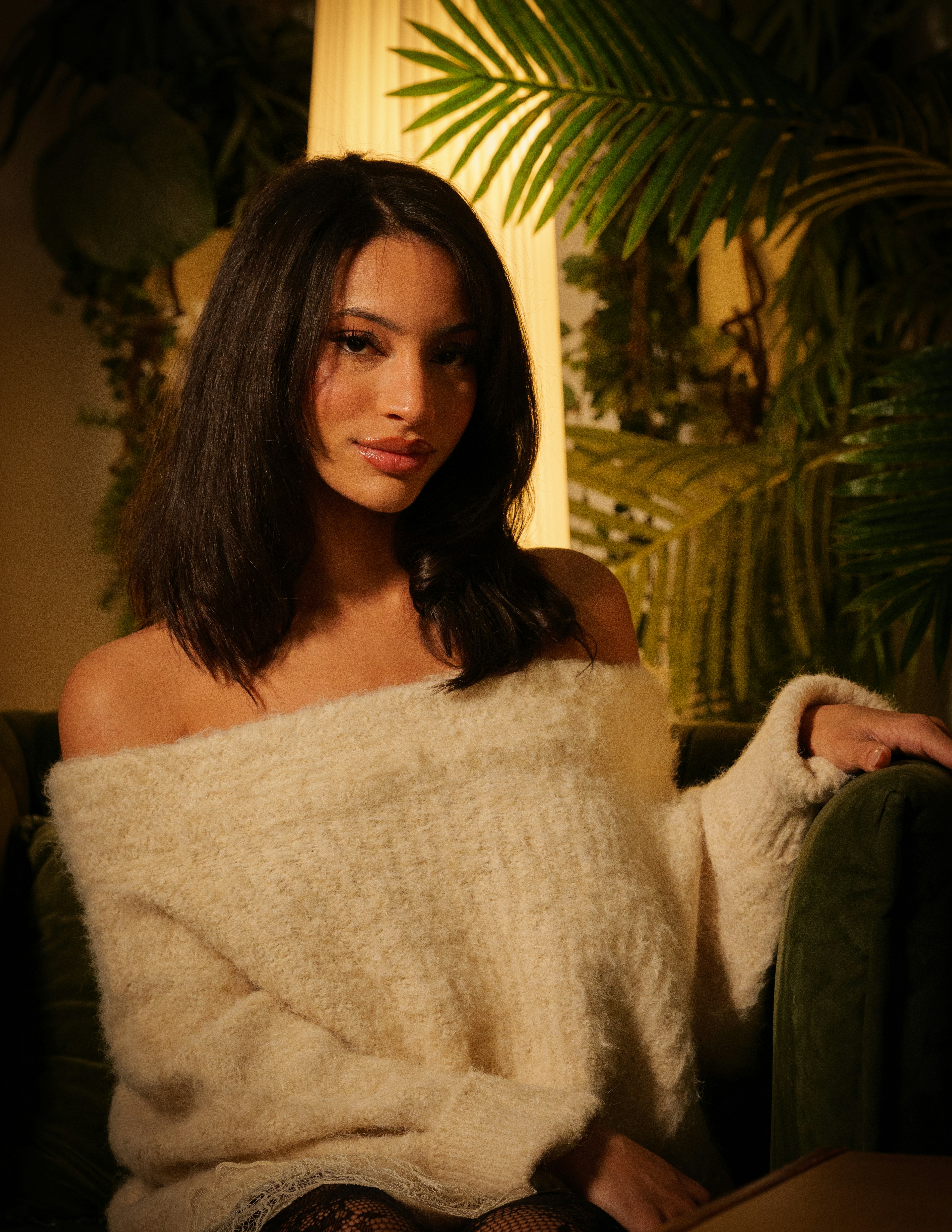 A woman in a cream sweater sits indoors.