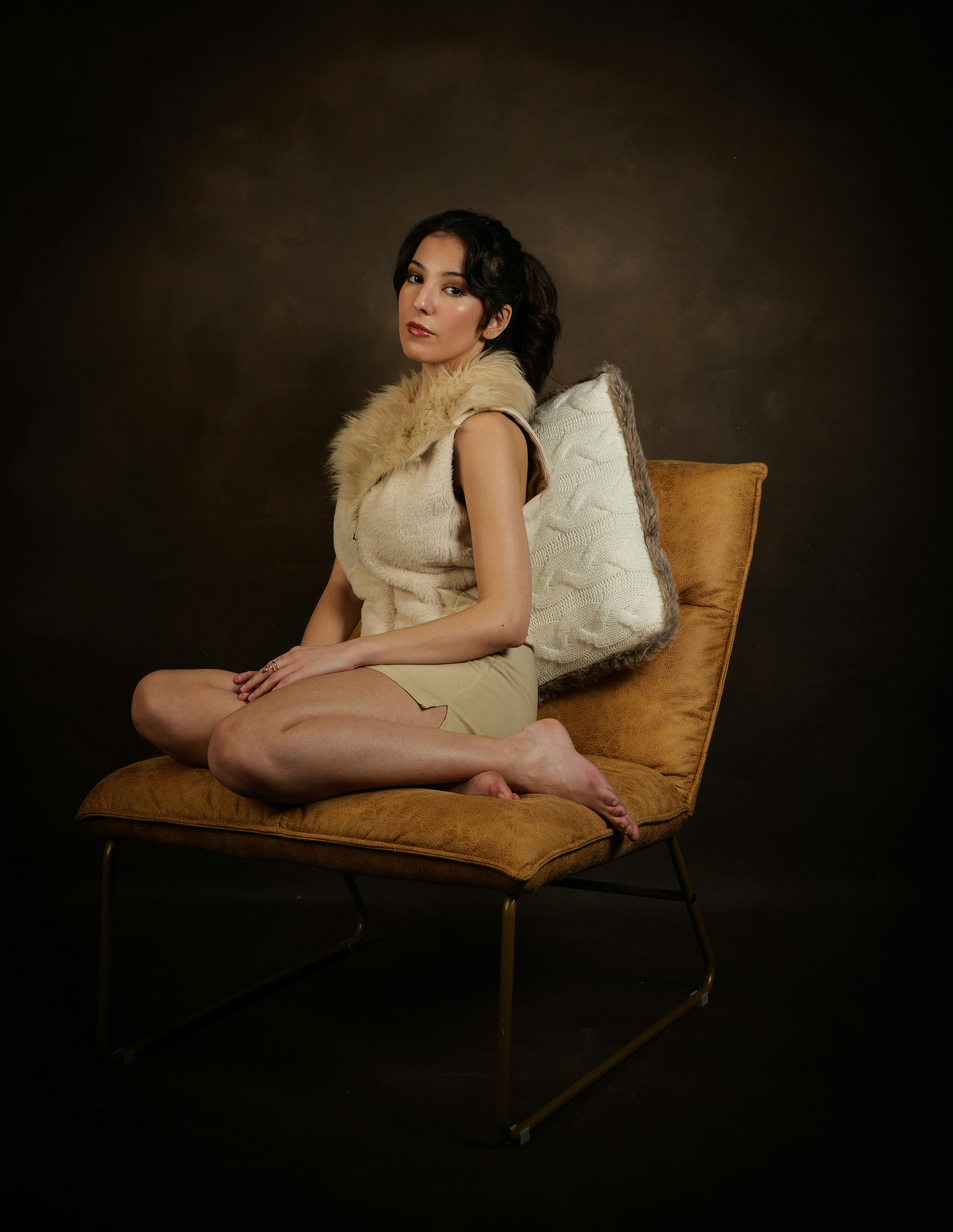 Woman in a fur collar sits on a chair.