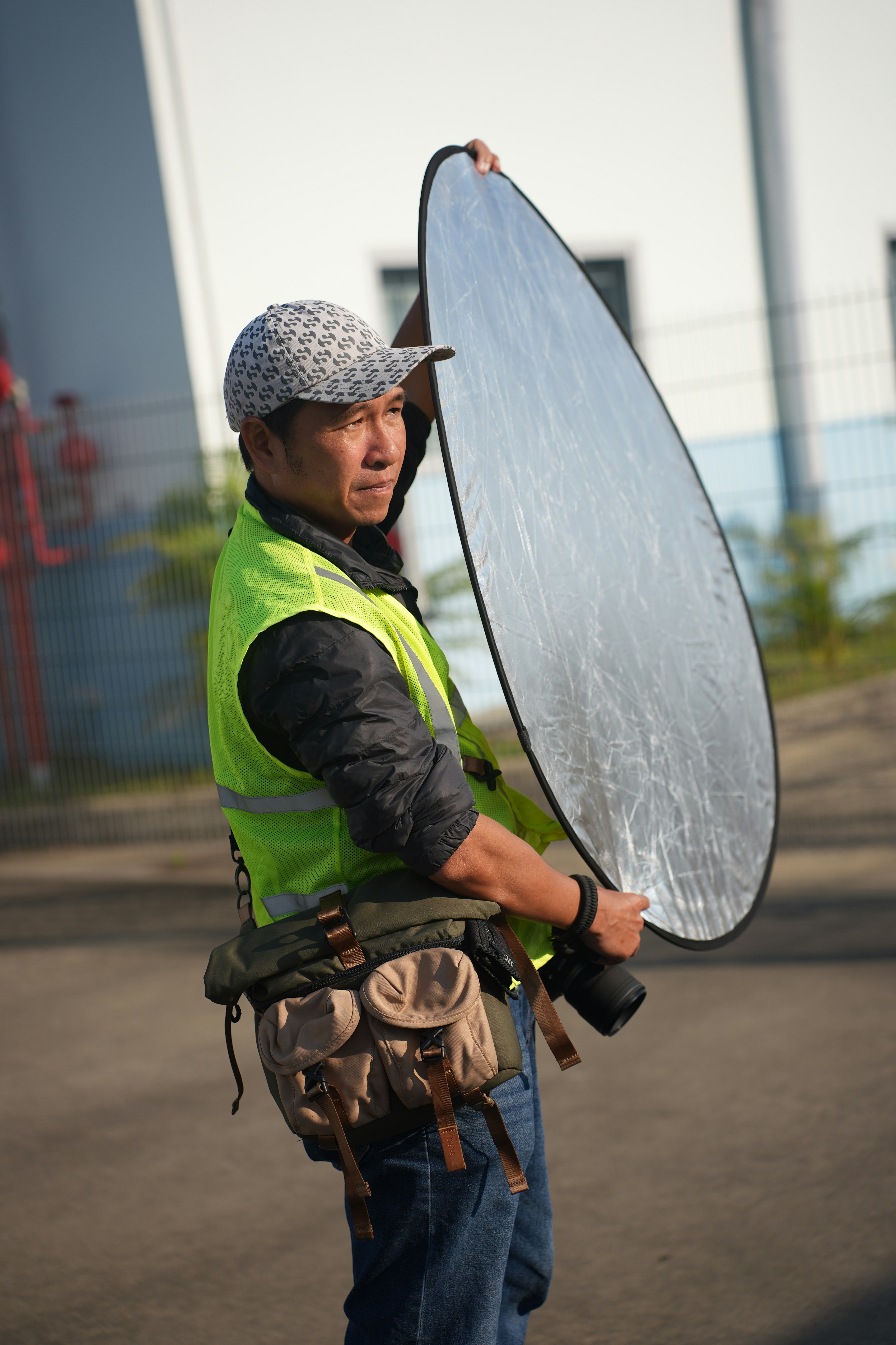 A man holding a reflective disc for photography.