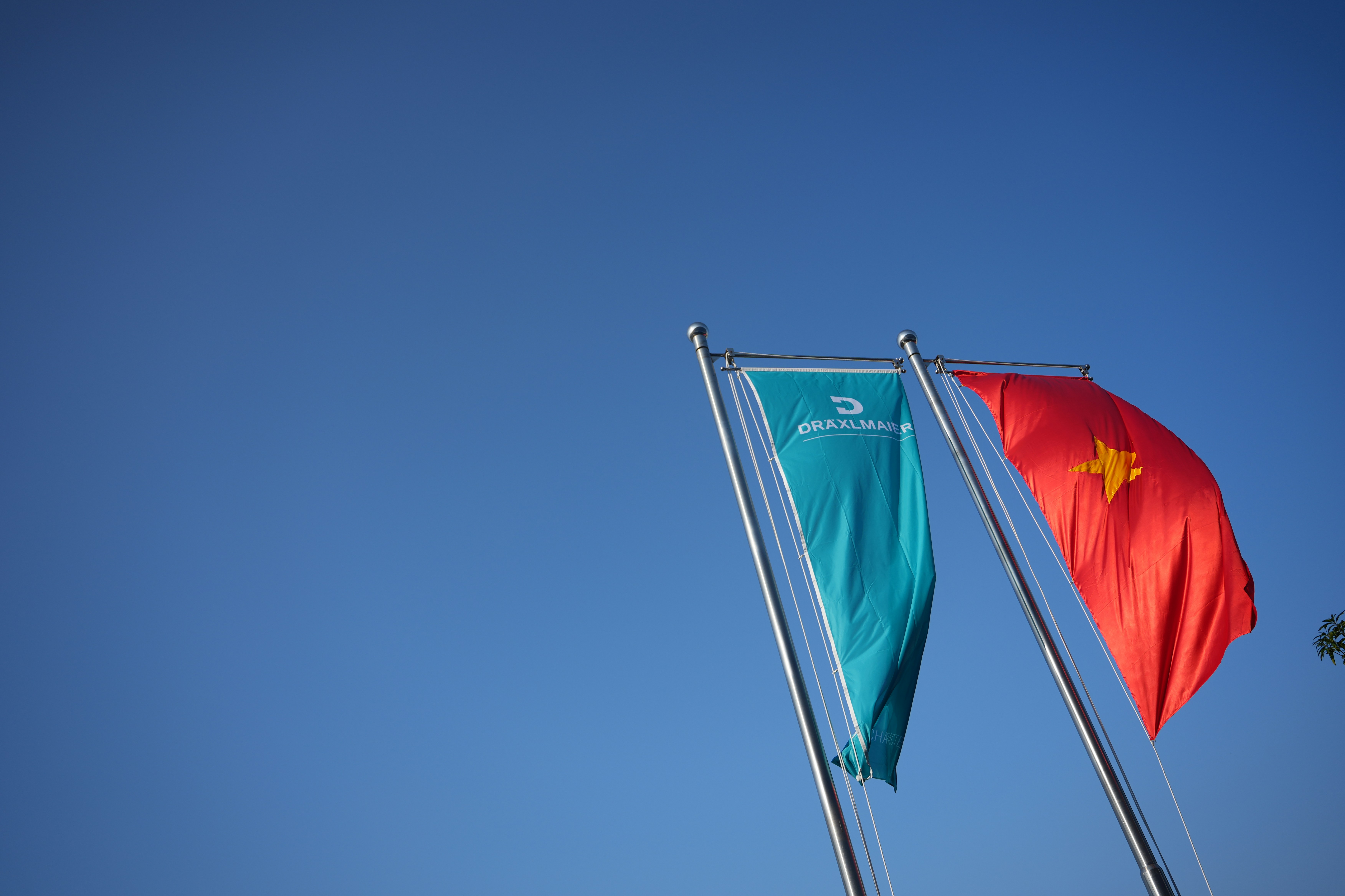 Two flags waving against a clear blue sky