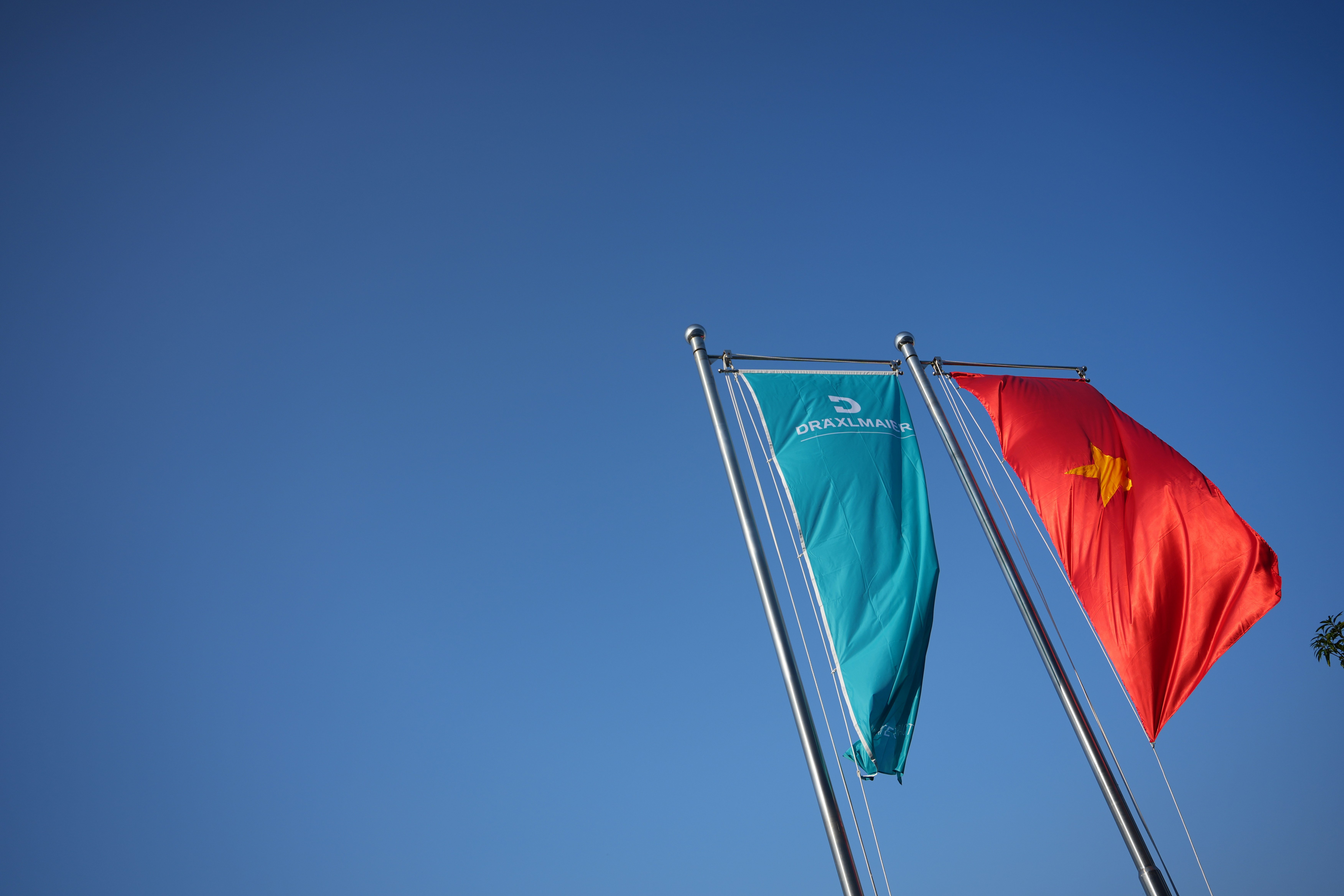 Two flags waving against a clear blue sky