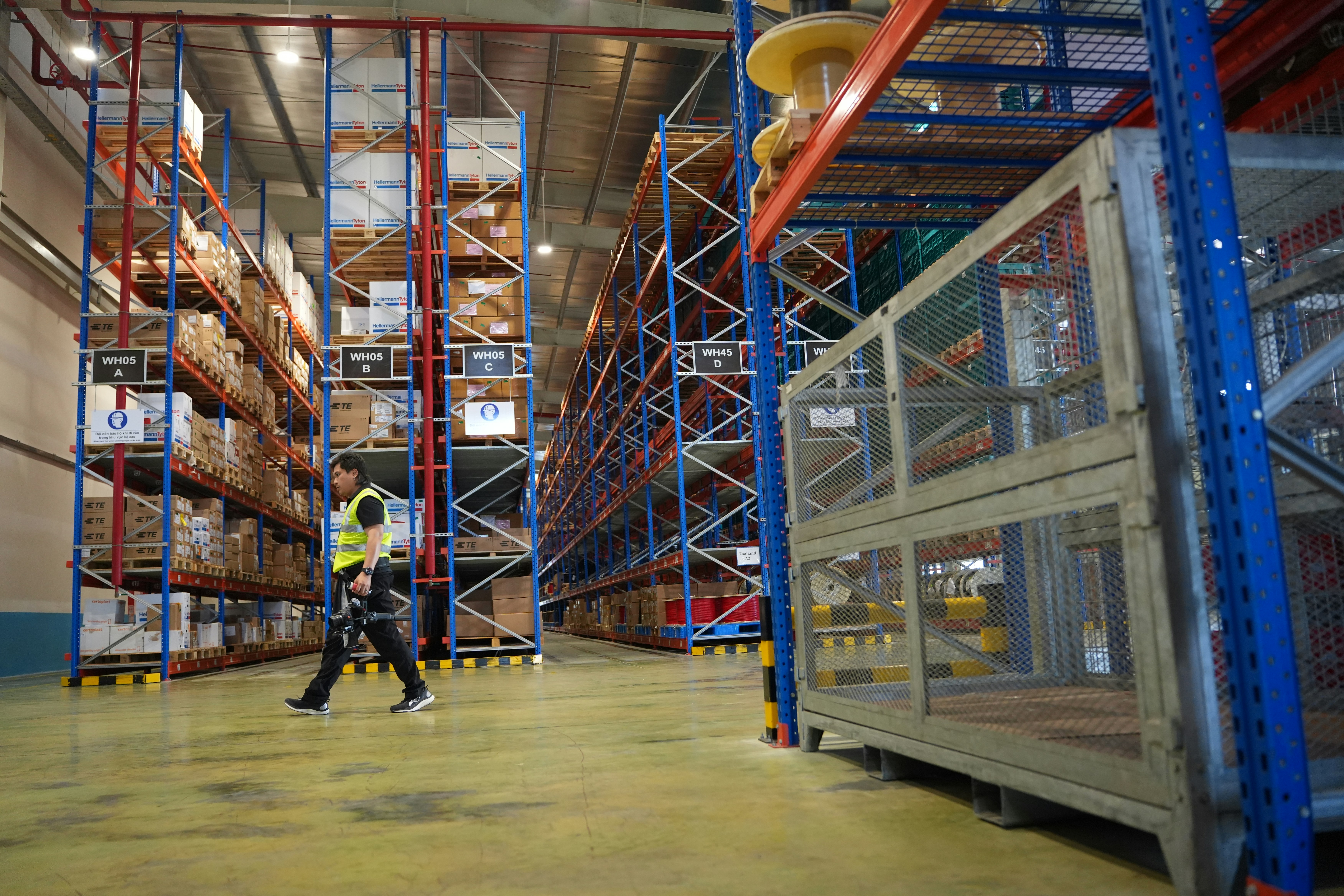 Man walks through a brightly lit warehouse with tall shelves.