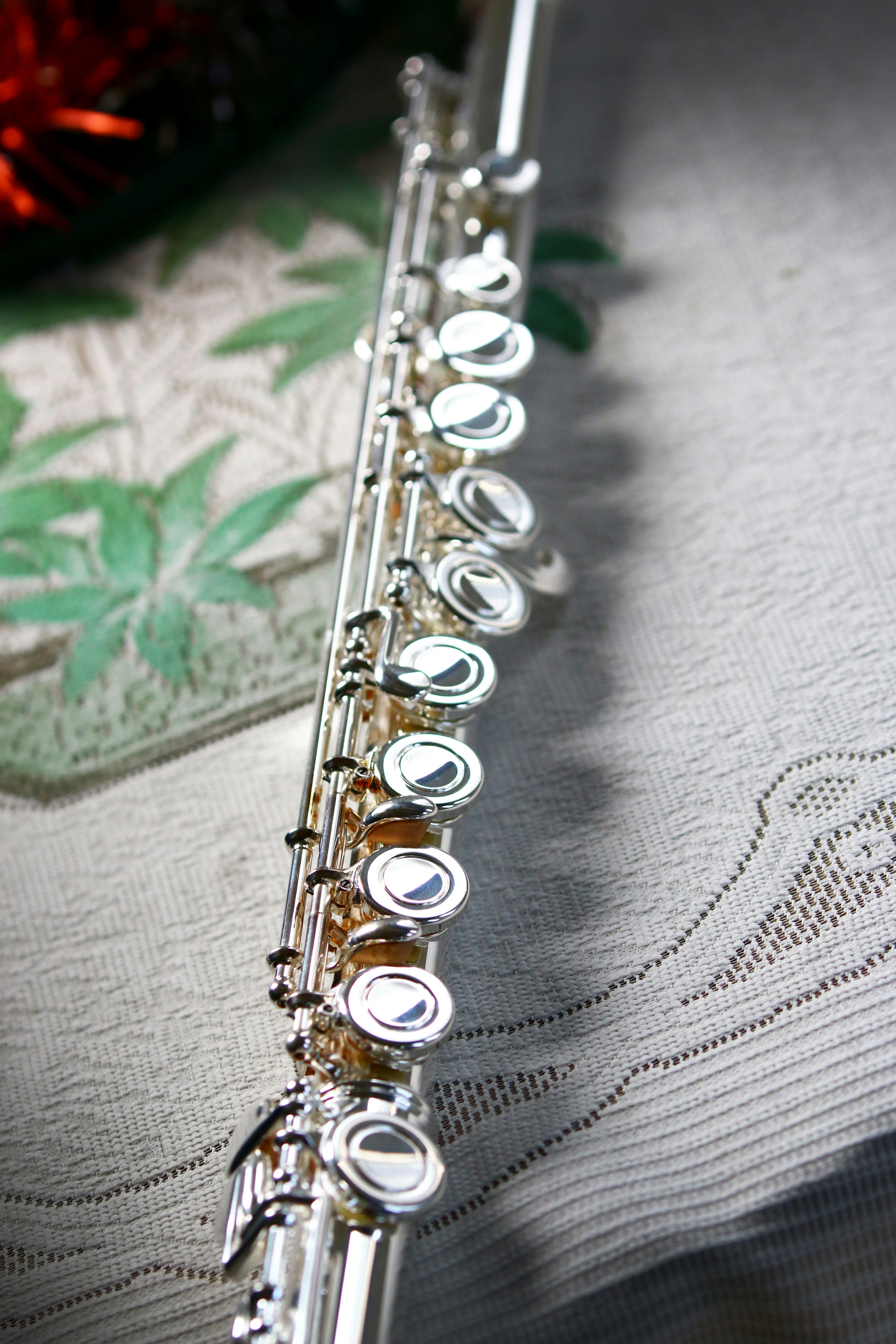 A silver flute rests on a patterned tablecloth.