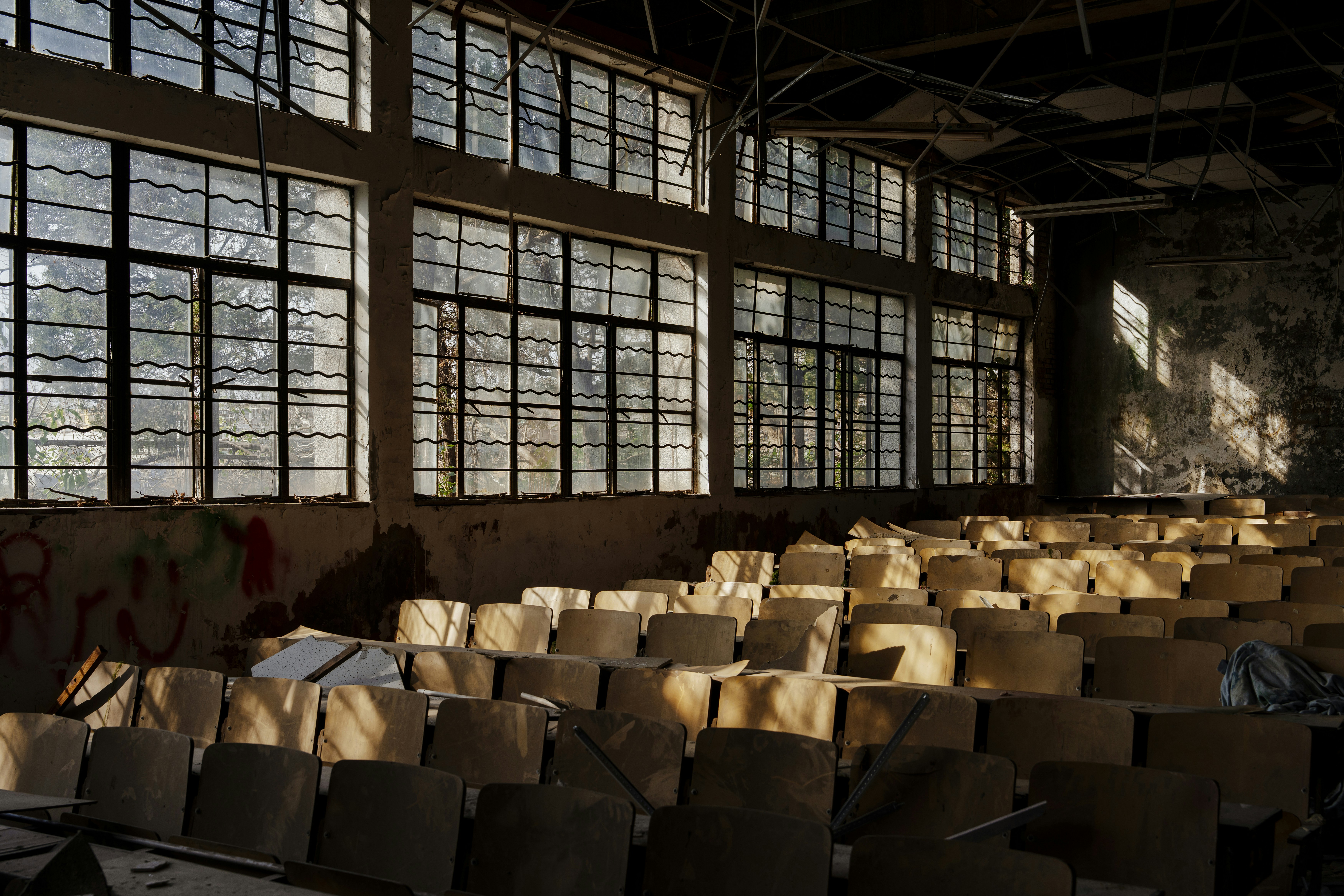 Rows of empty chairs in a sunlit abandoned hall