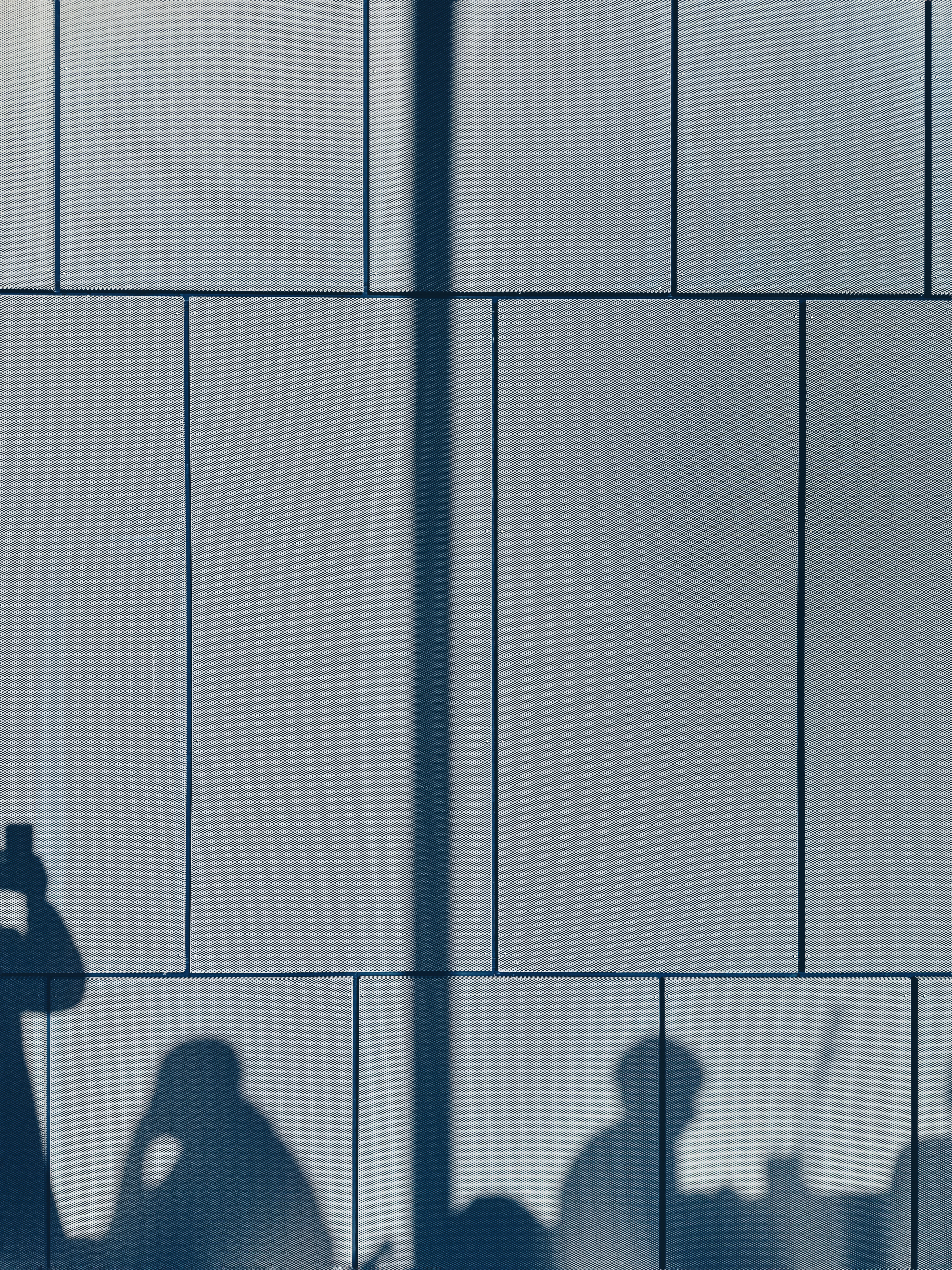 Sombras de pessoas contra uma parede de azulejos.