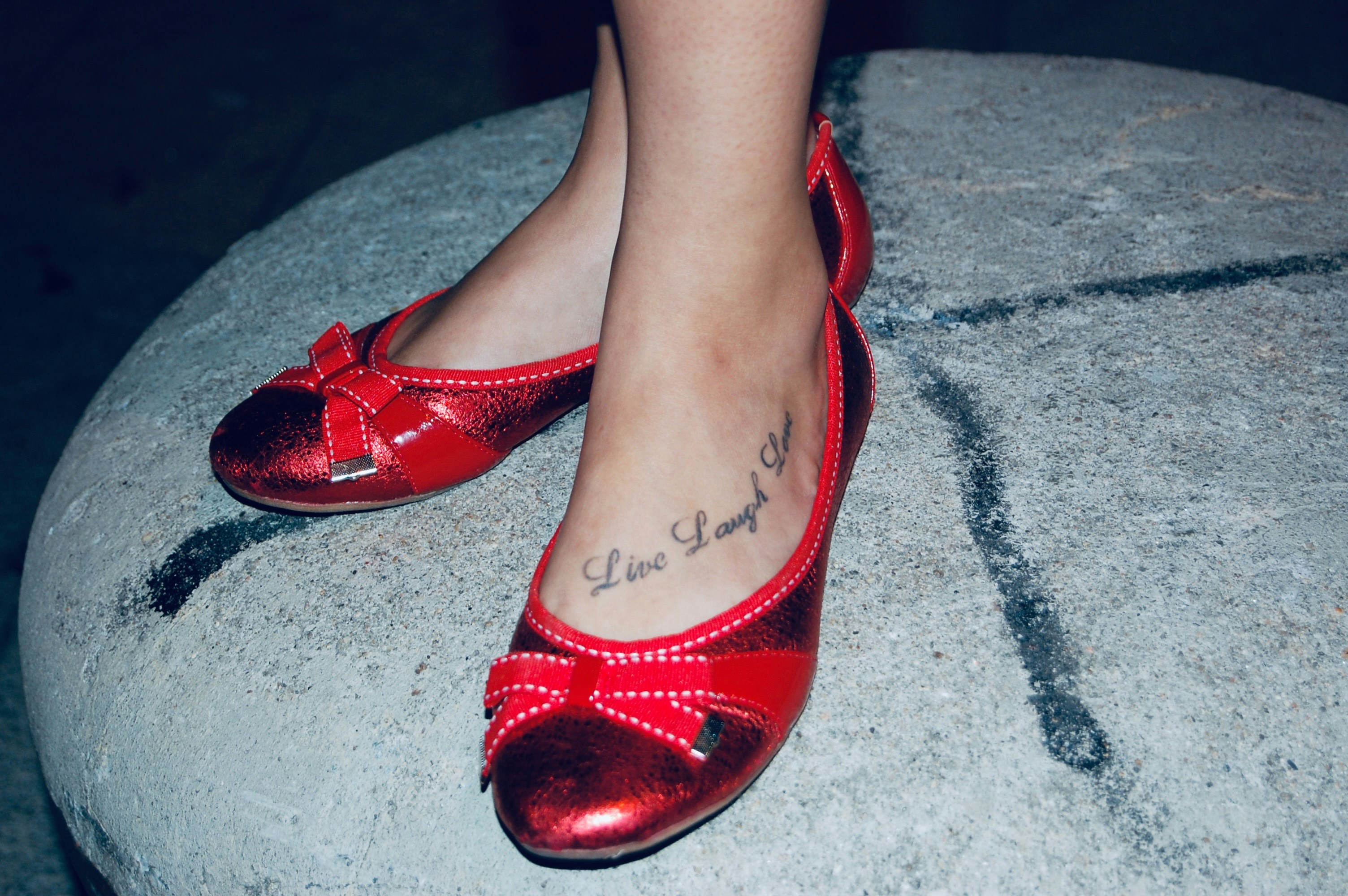 Red ballet flats with bows on a stone