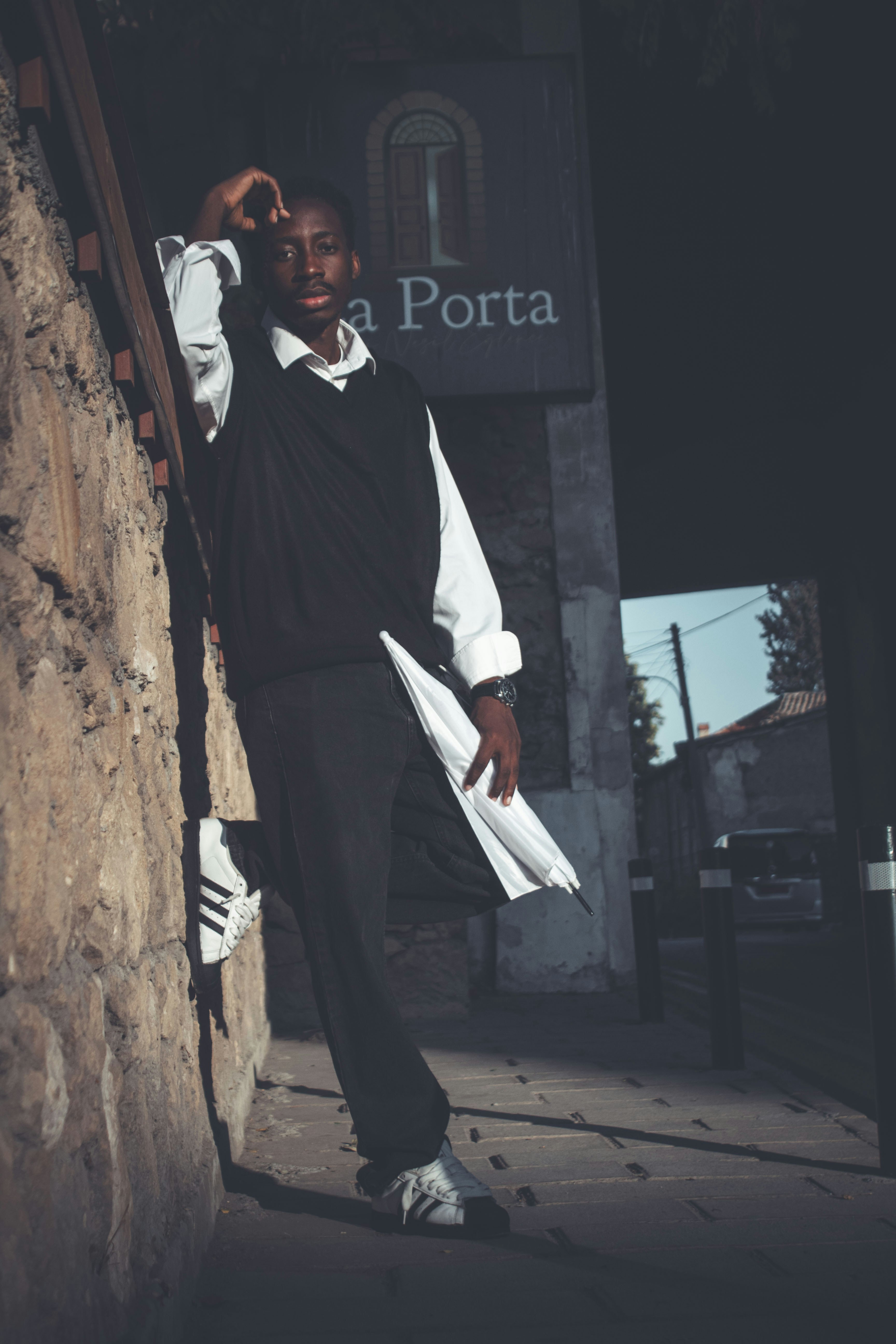 Young man in formal wear holding umbrella outside