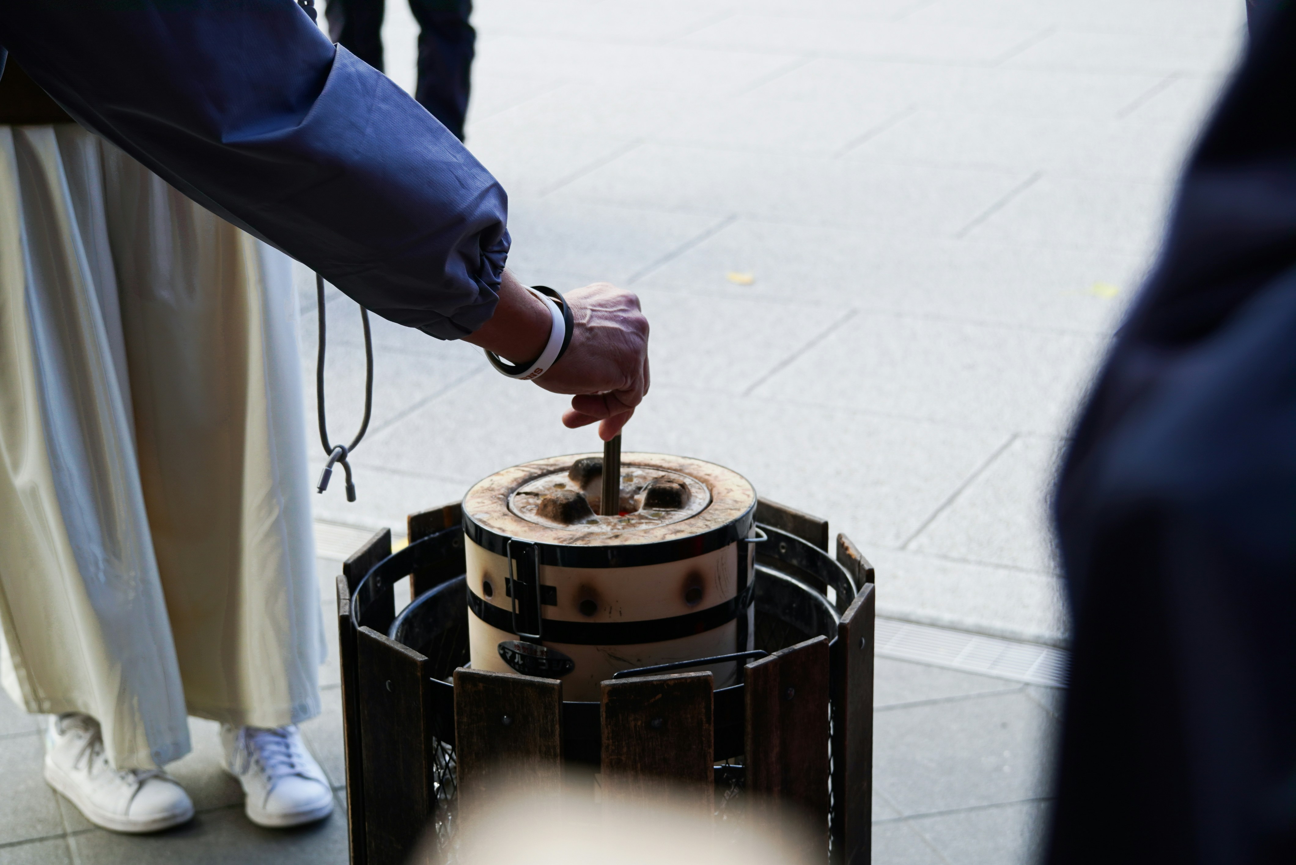 Person's hand using a stick on a wooden object.