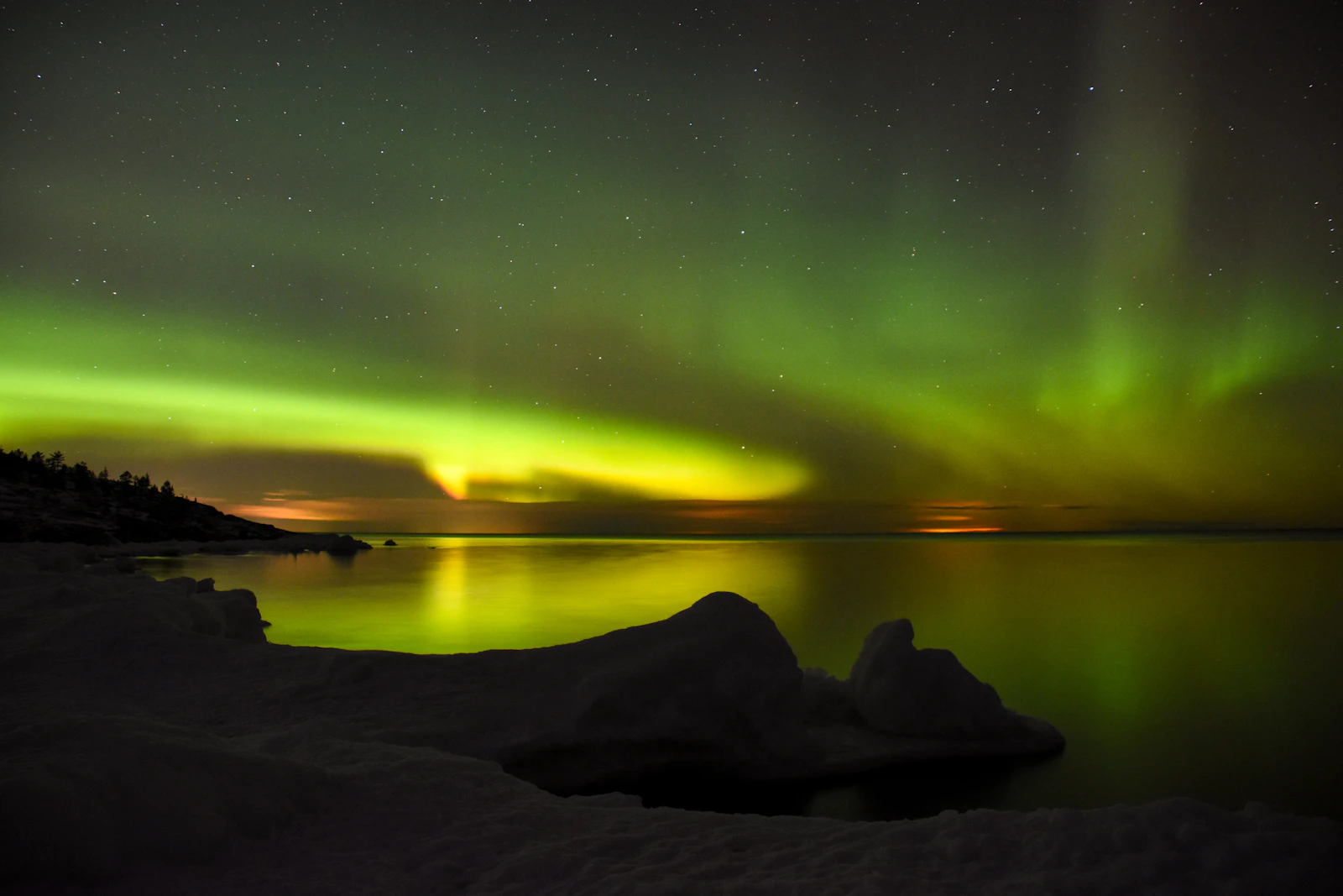 Aurora reflected on calm water in northern Sweden