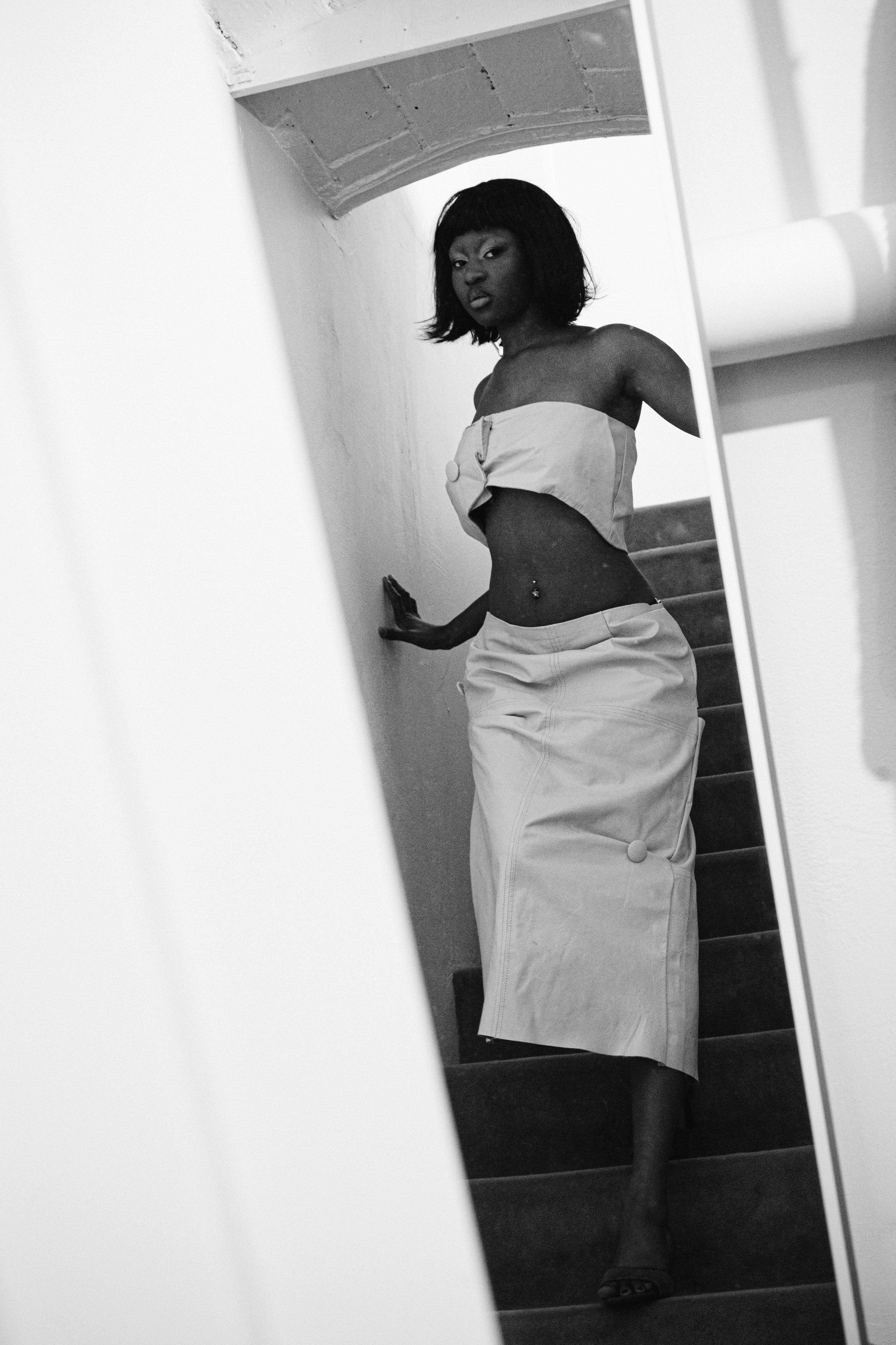 A woman walks down a staircase in a white outfit.