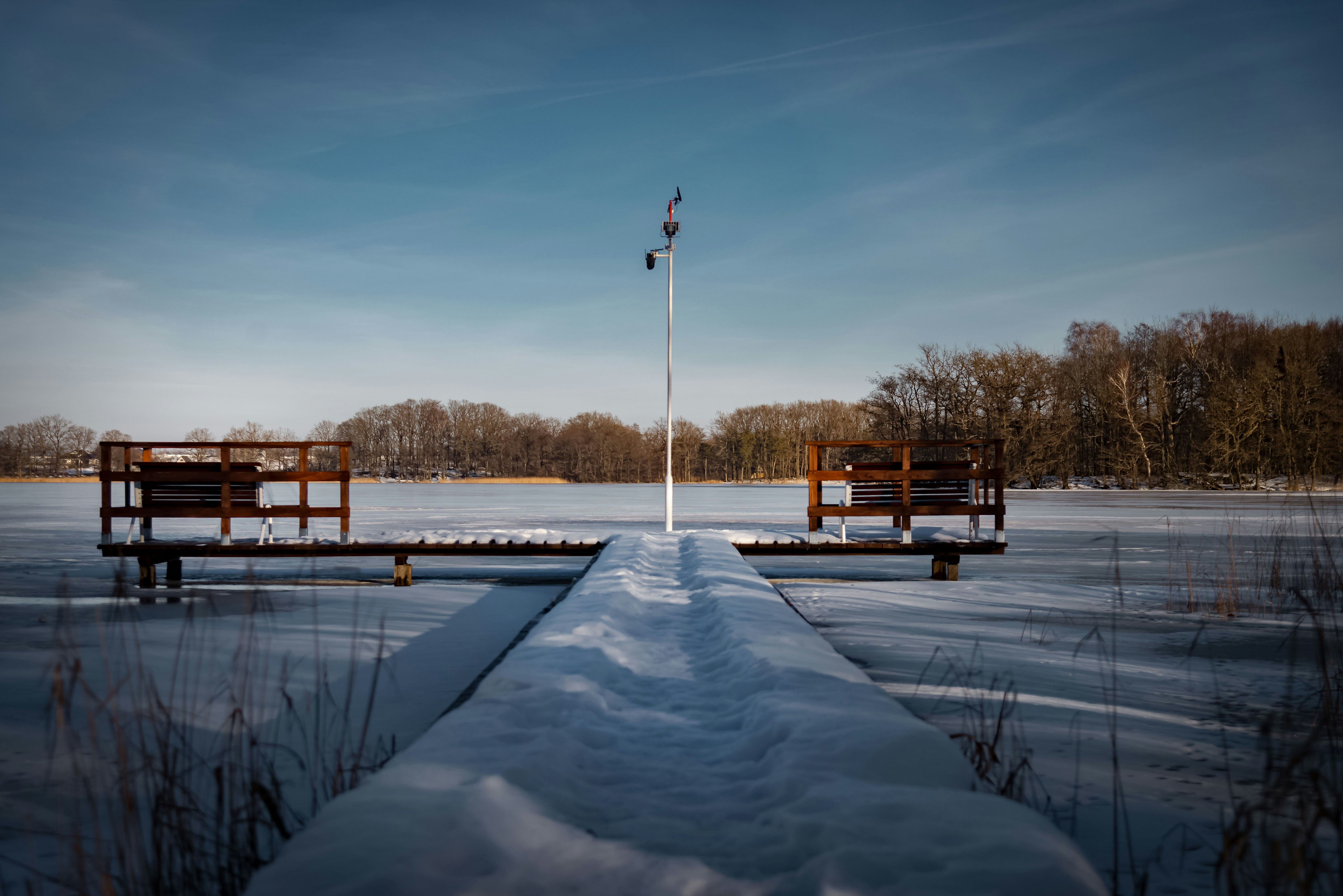 Snow covered pier on a frozen lake in winter.
