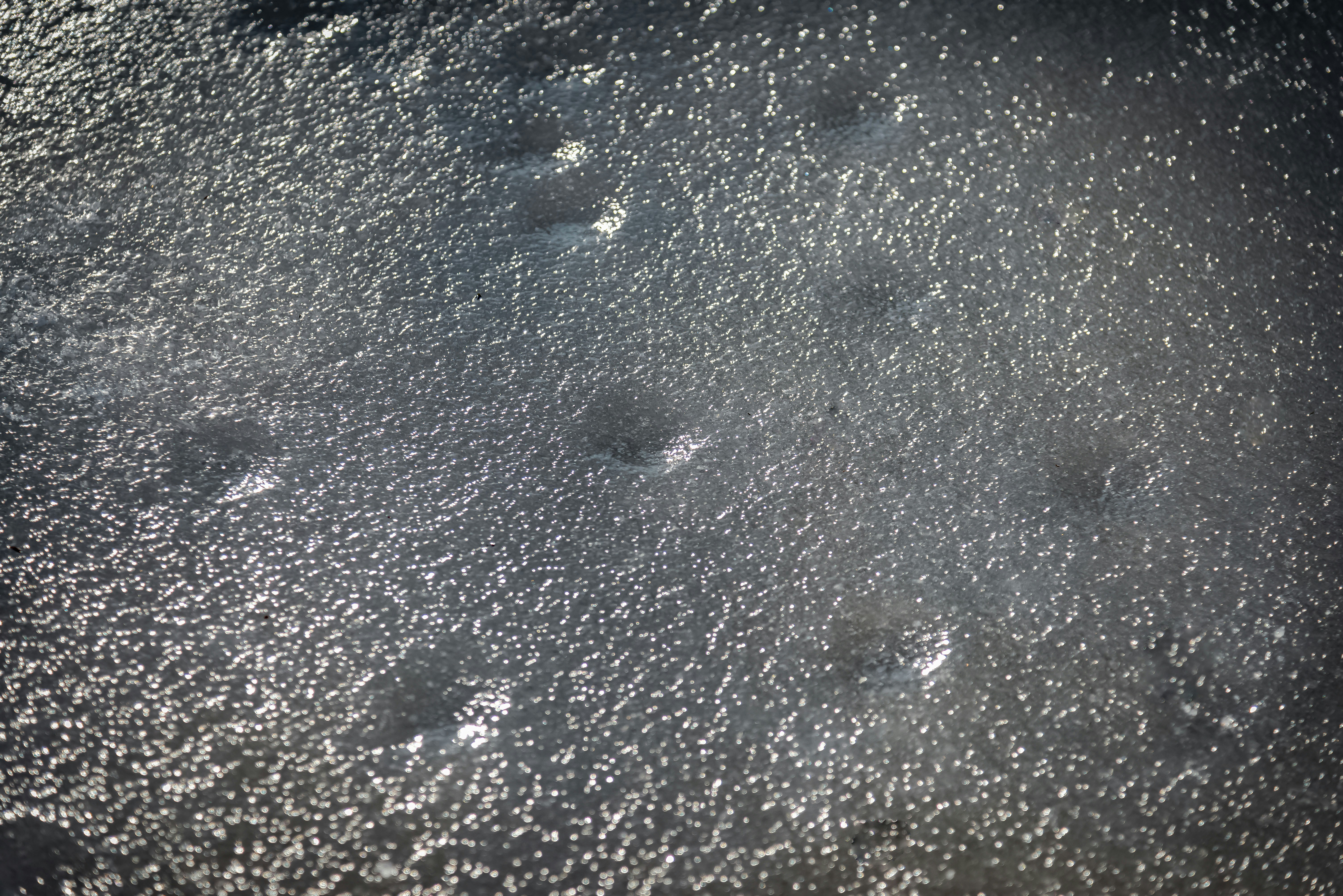Close up of ice with small bubbles and cracks.